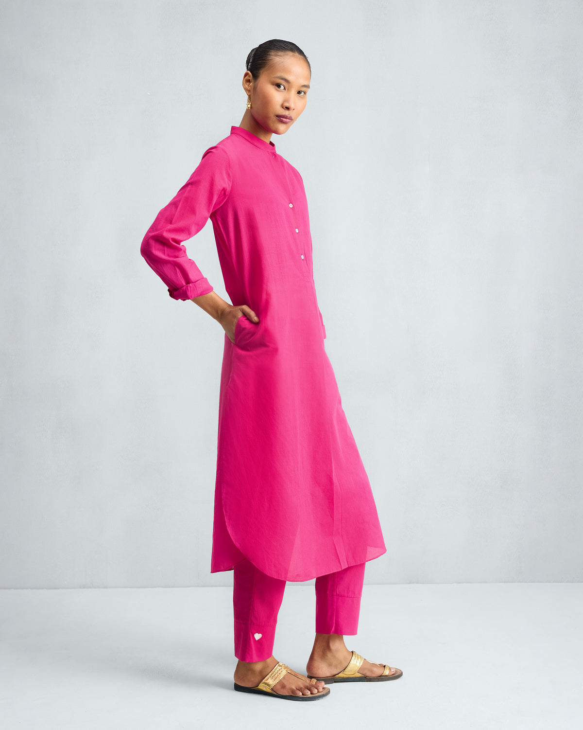 Side view of a fuchsia long kurta set with matching trousers.
