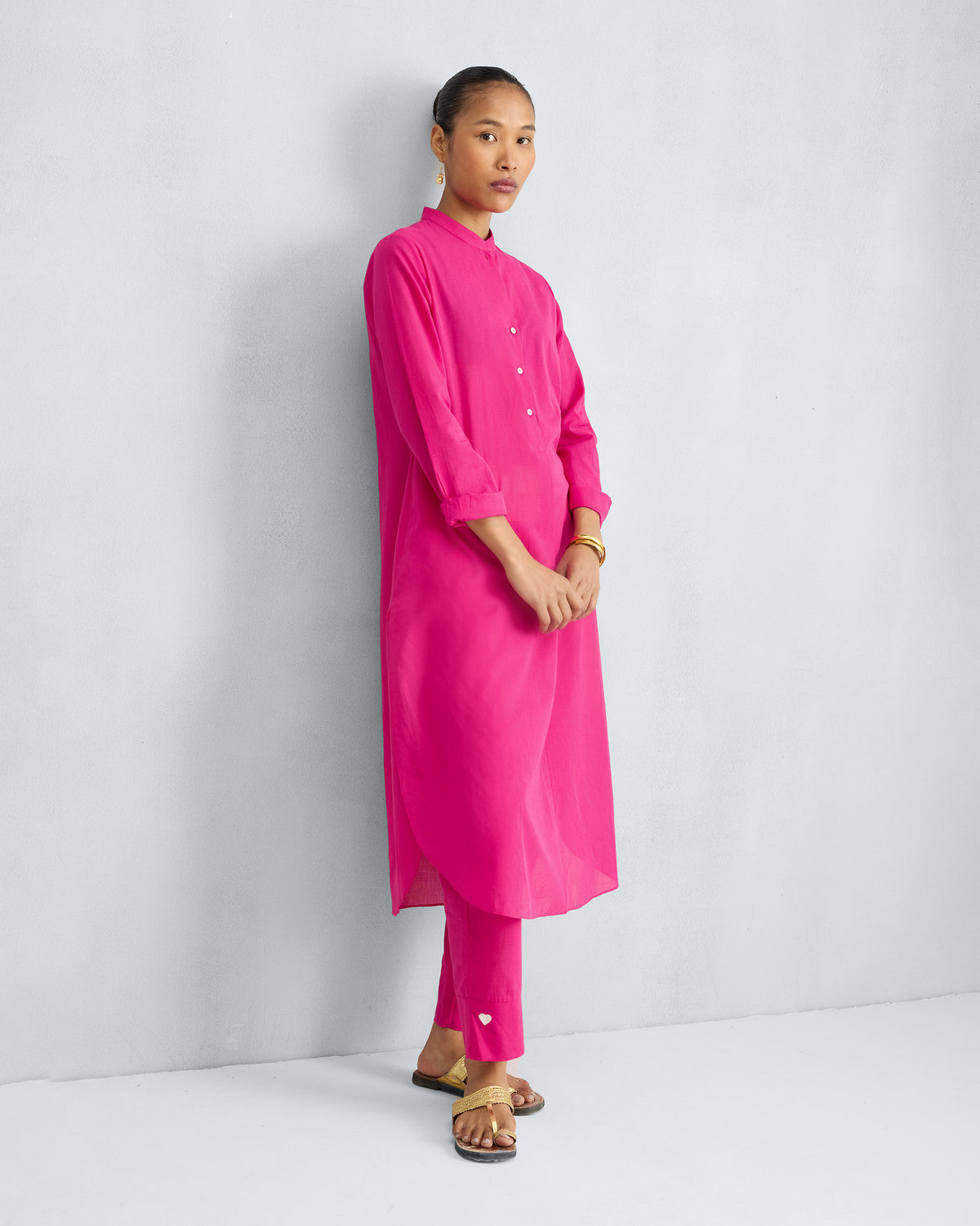 Person wearing a fuchsia kurta set with a white heart on the trouser hem.