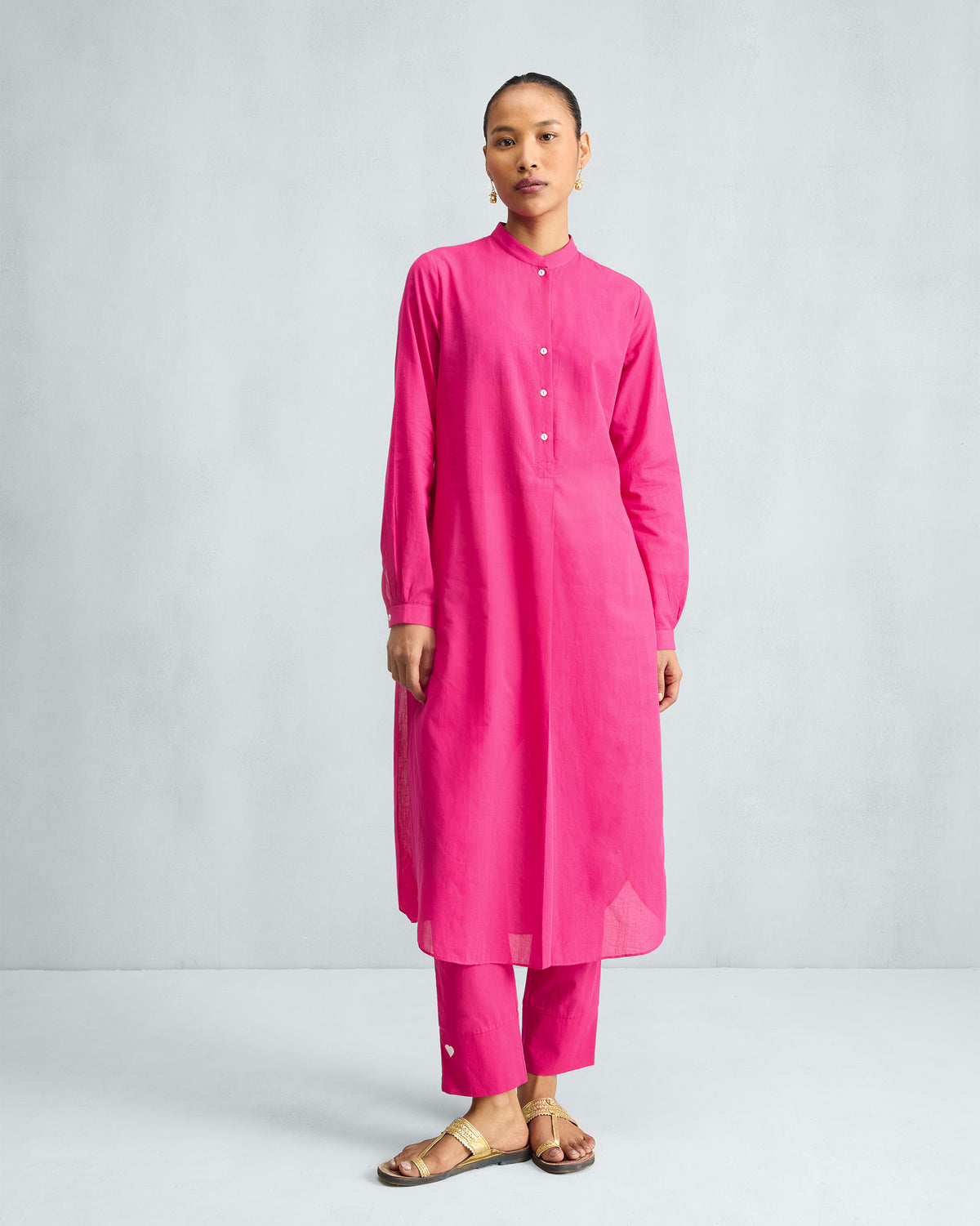 Person wearing a fuchsia long kurta with a buttoned mandarin placket.