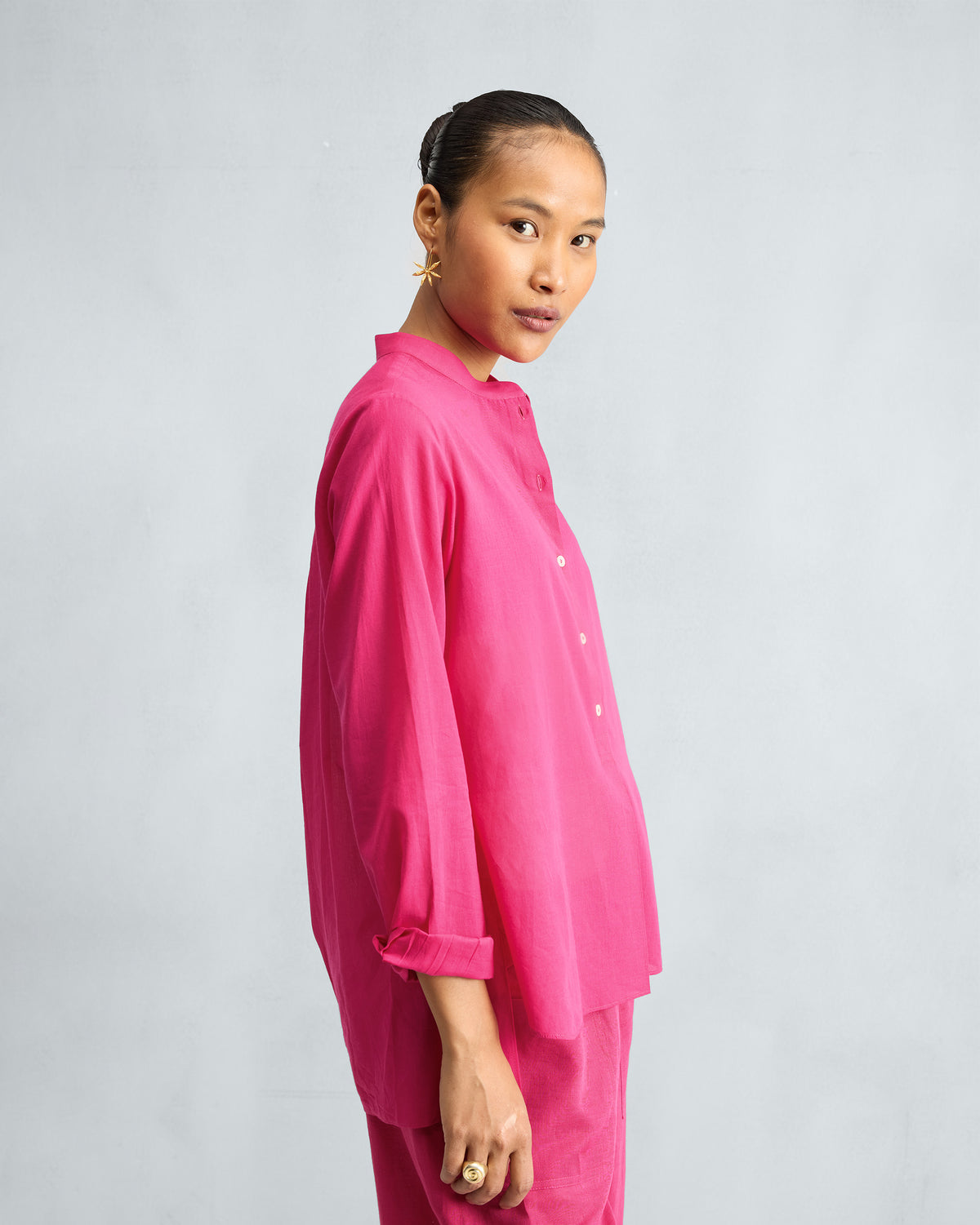 Side view of a fuchsia mandarin collar top with a button placket.
