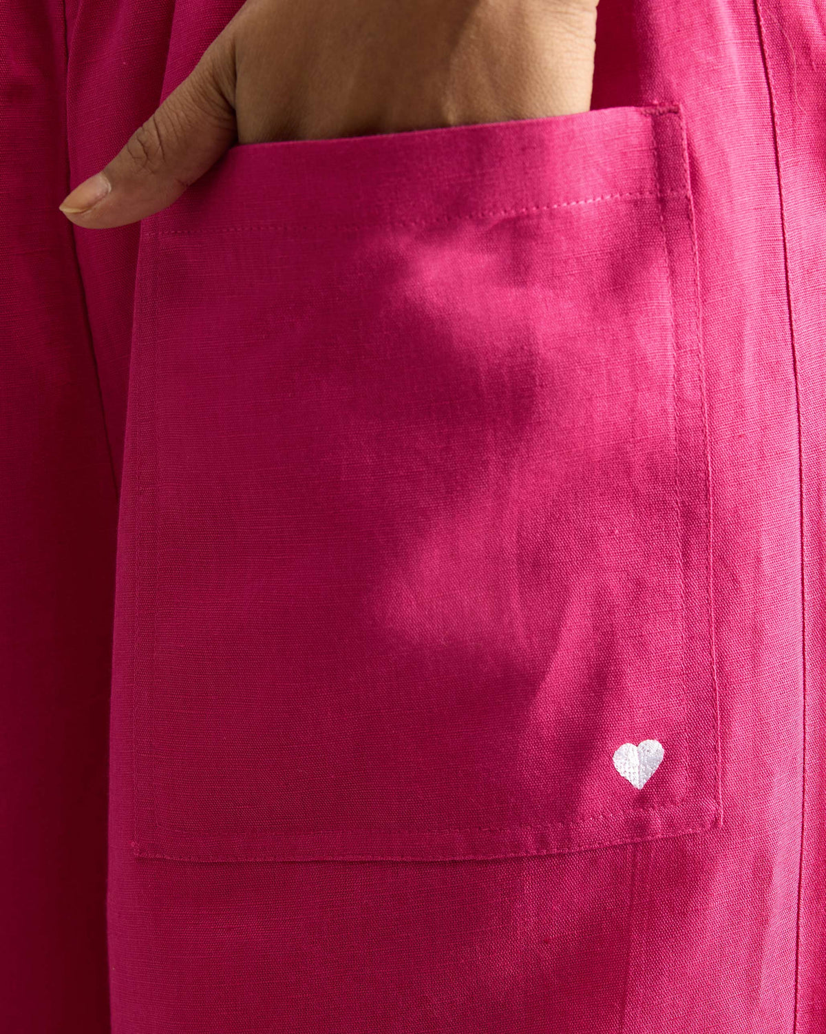 Close-up of a fuchsia patch pocket with a white heart embroidery.
