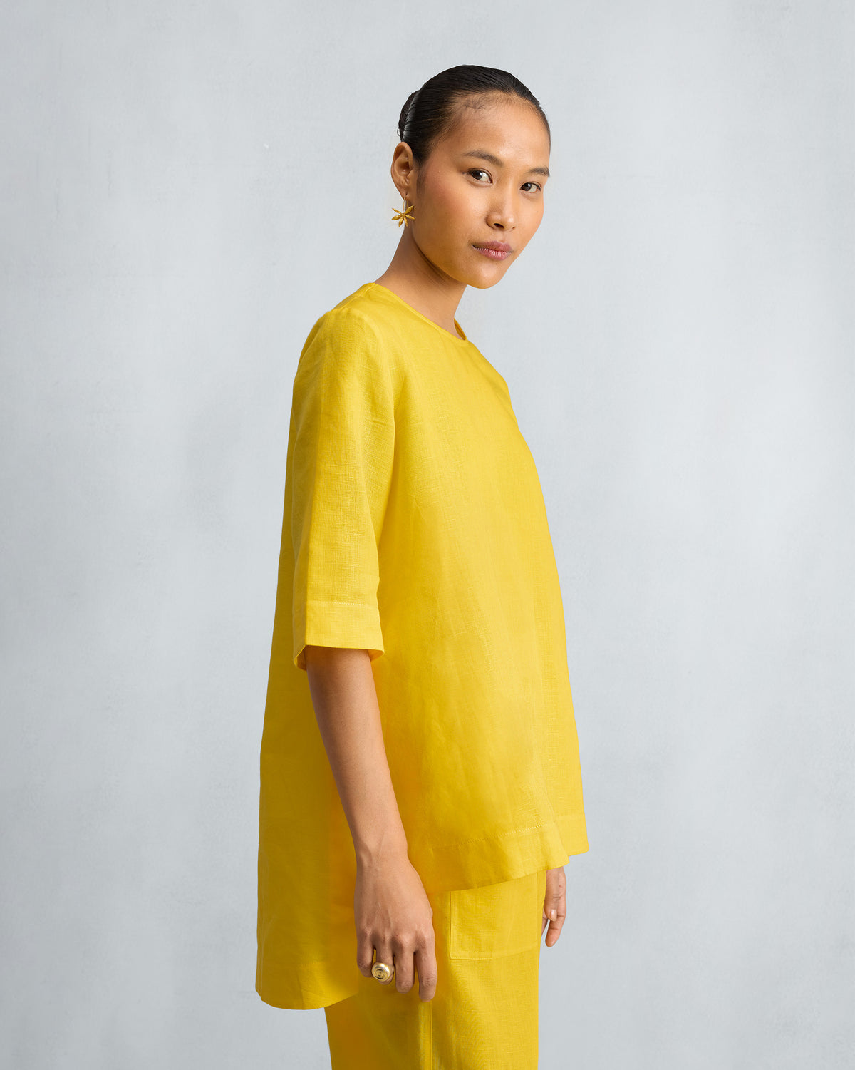 Side view of a yellow high slit top set showing the high-low hem.