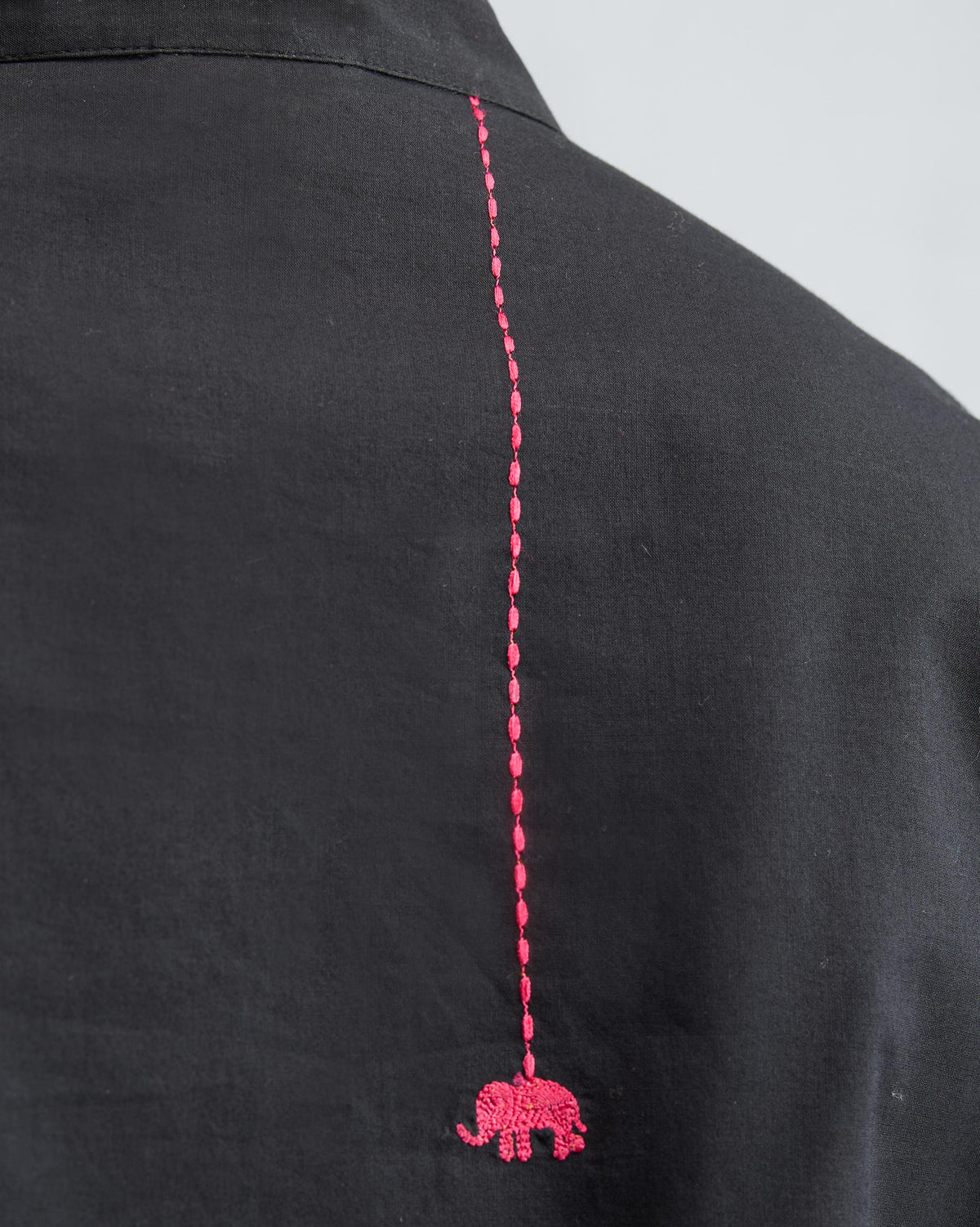 Close-up of a pink elephant embroidered on a black kurta back.