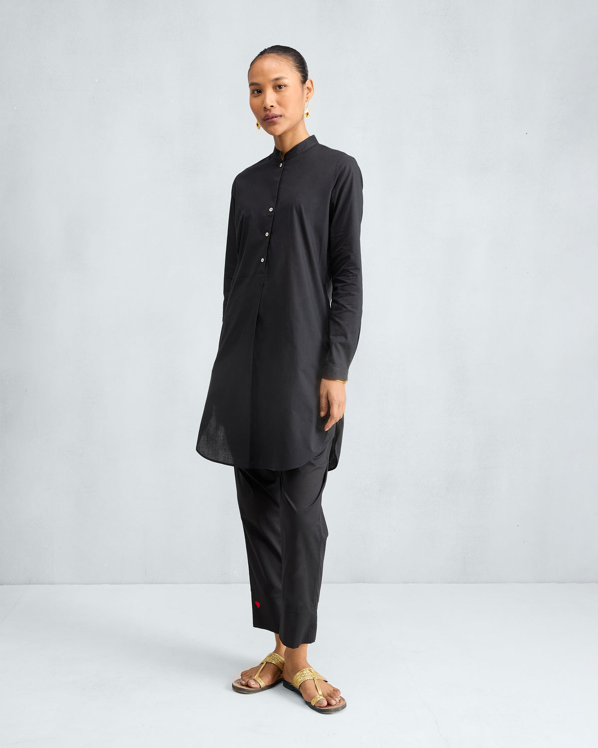 Person wearing a black mid-length kurta set at a three-quarter angle.