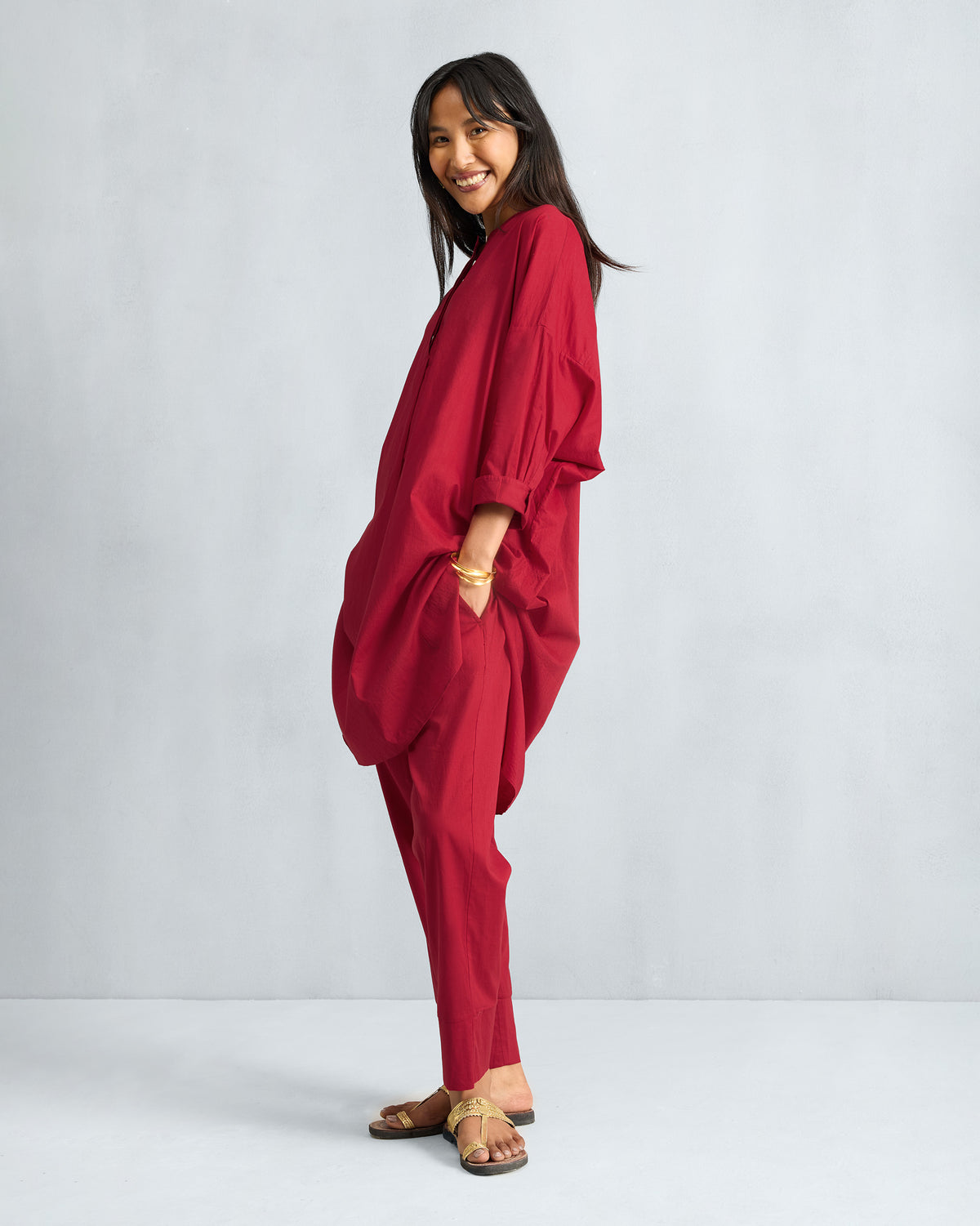 Person wearing a red Lazy Sunday tunic set with hands in the side pockets.