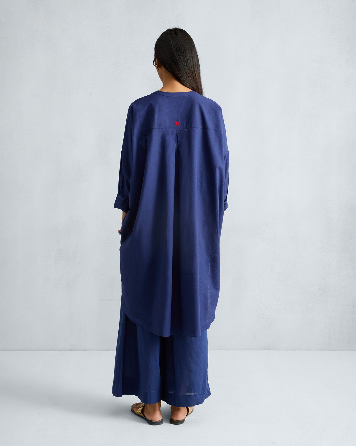 Back of the ink blue Lazy Sunday tunic worn by a person, with a small red star on the yoke.