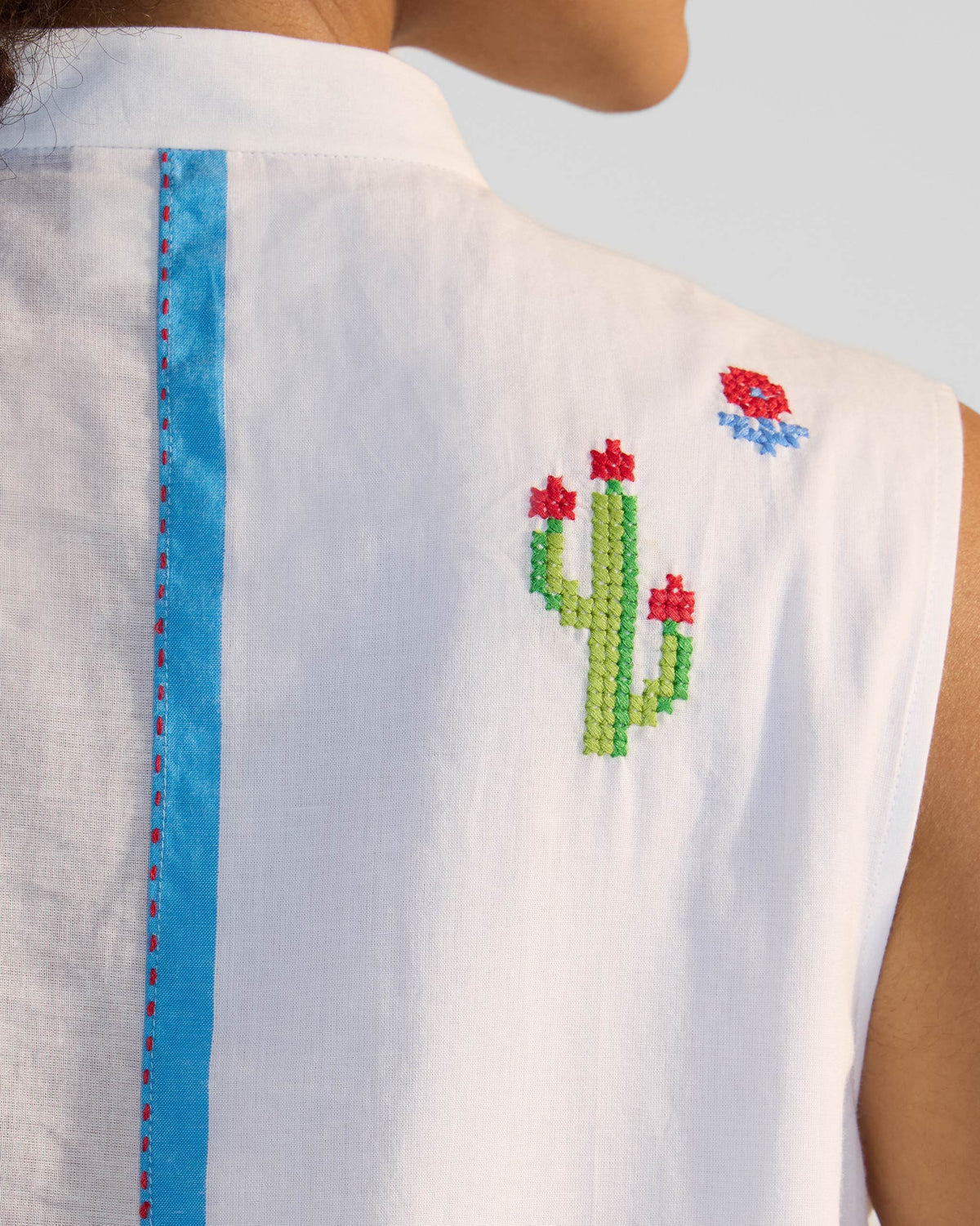 Close-up of cactus embroidery beside the blue strip on a white Riha kurta.