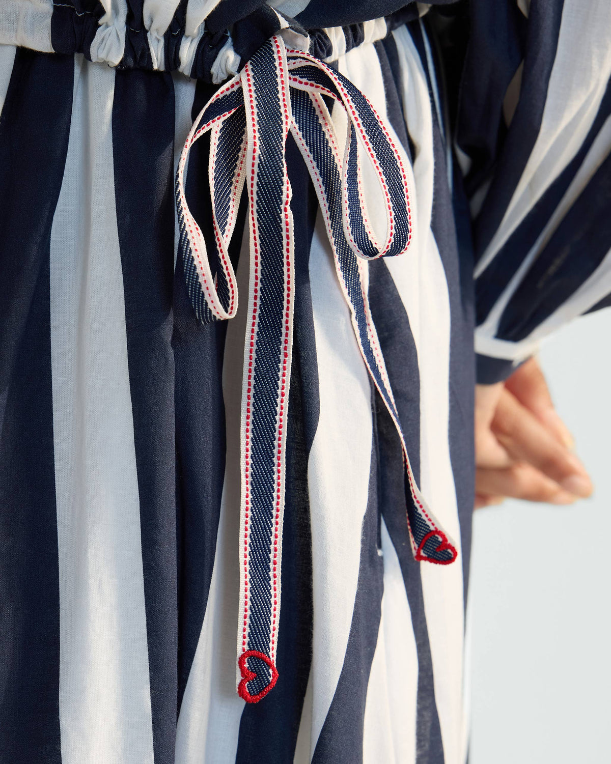 Close-up of the heart-ended drawstring on a navy and white striped Zaya top.