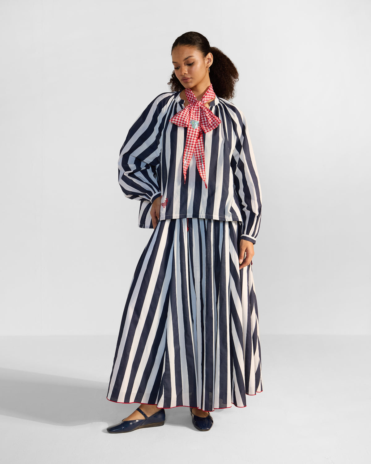 Person wearing a navy and white striped Zaya Top Set with a red bird near the hem.