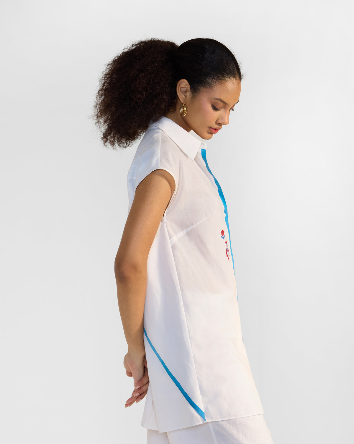 Side view of a white sleeveless Eira top with blue selvedge trim.