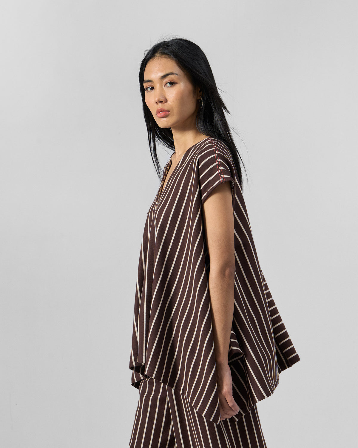 Side view of a brown and ivory striped kaftan top with a deep V-neck.