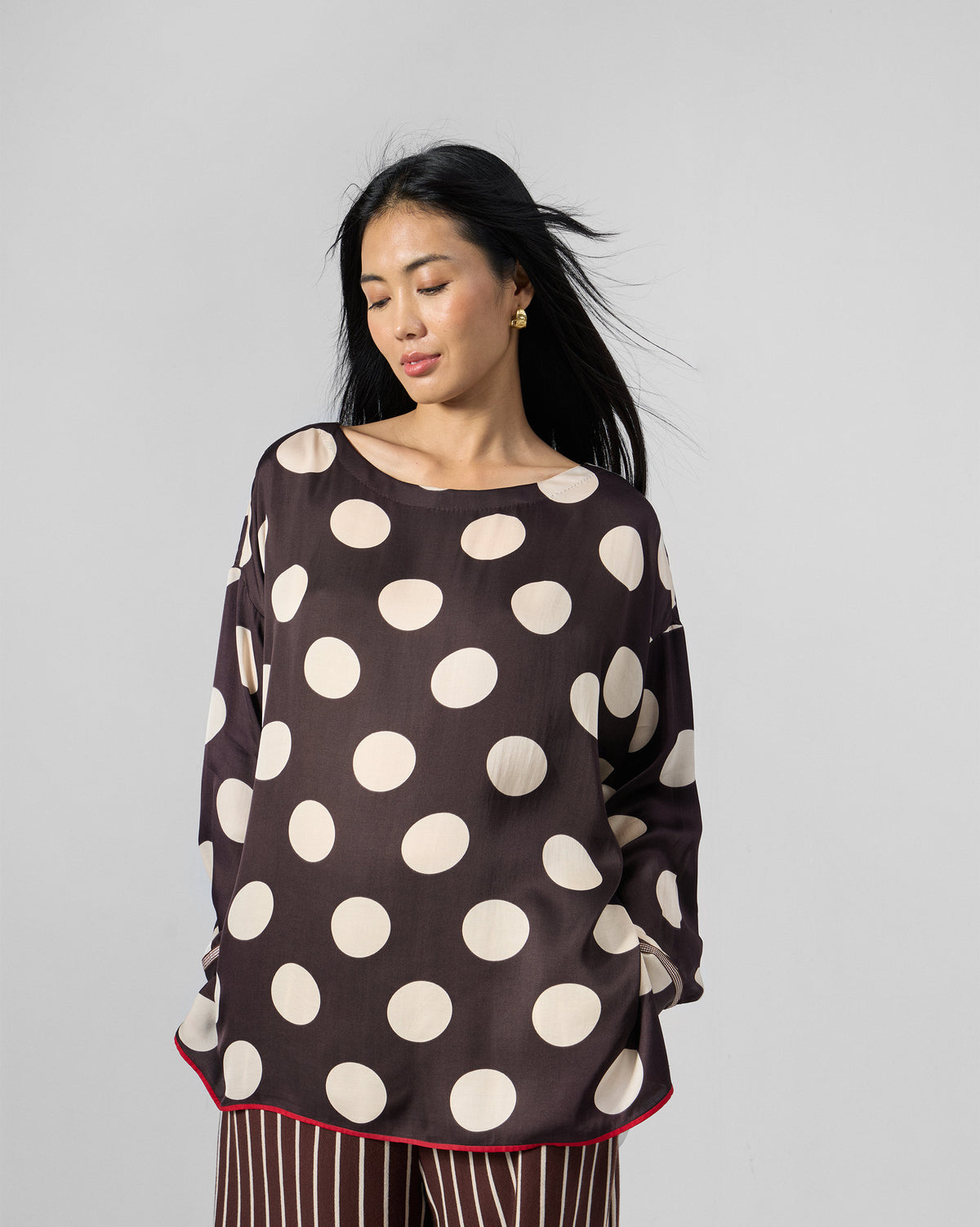 Person wearing a brown polka-dot top with side pockets.