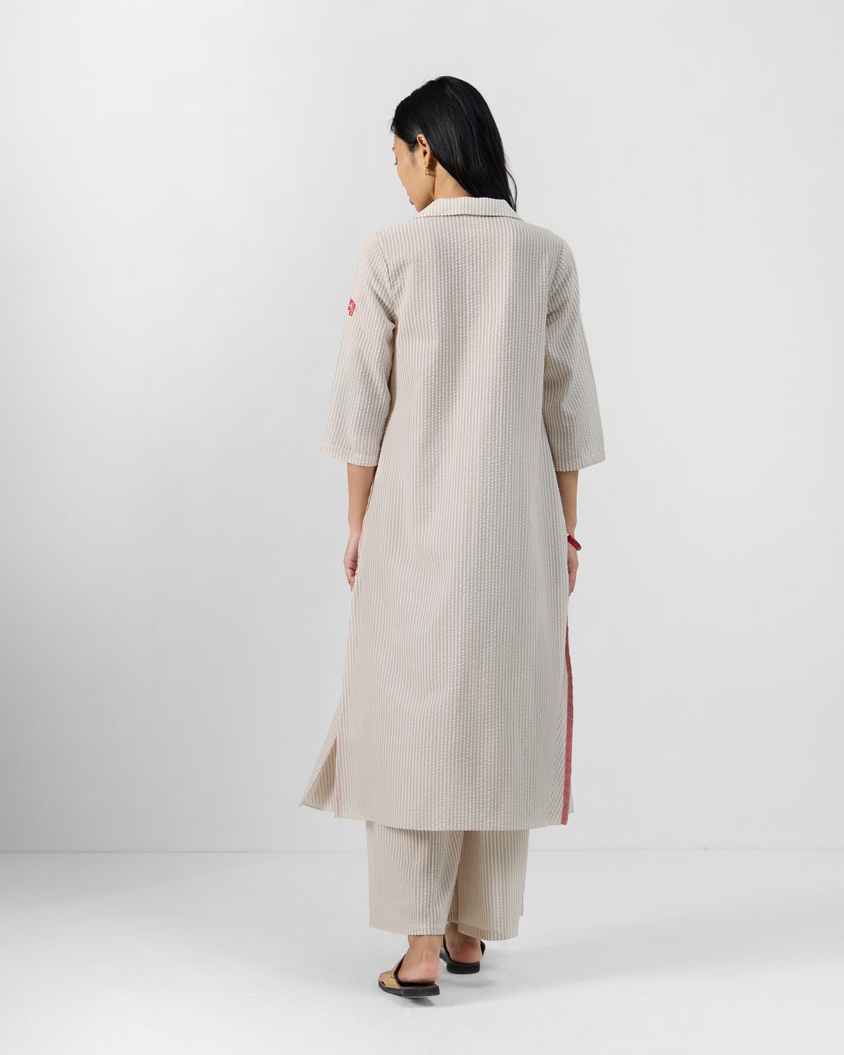 Back of a brown and ivory striped Maner Kurta Set with side slits.