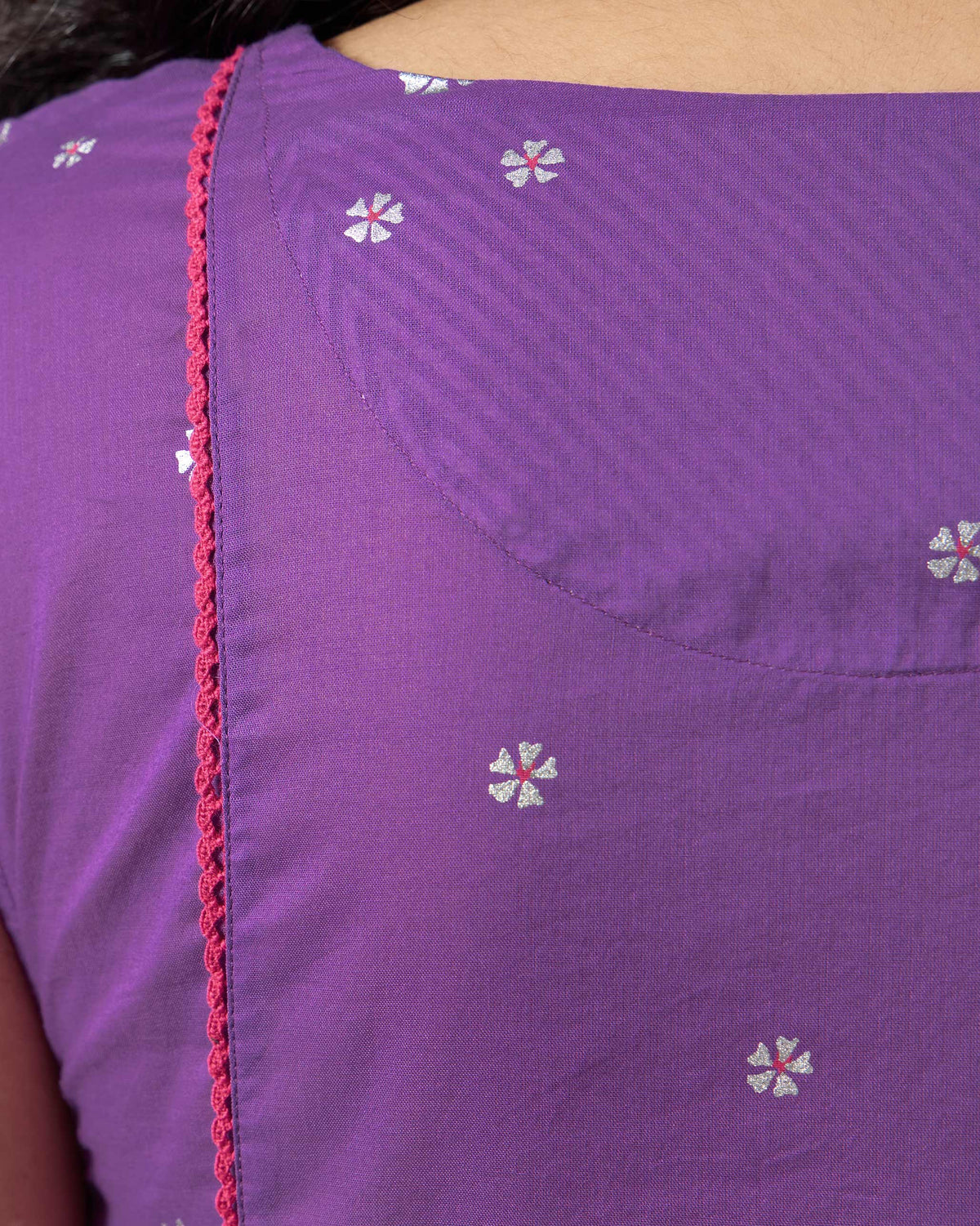 Close-up of purple kurta fabric with silver flowers and pink lace.