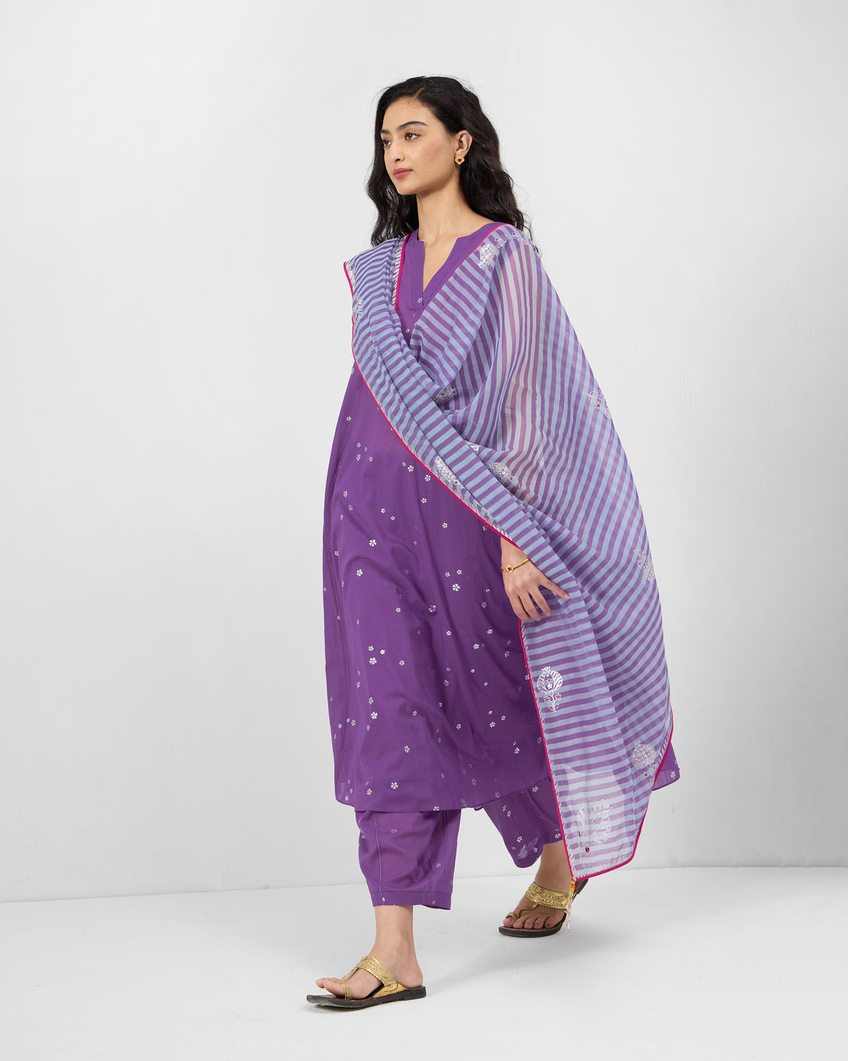 Person wearing a purple floral kurta set with a striped dupatta.
