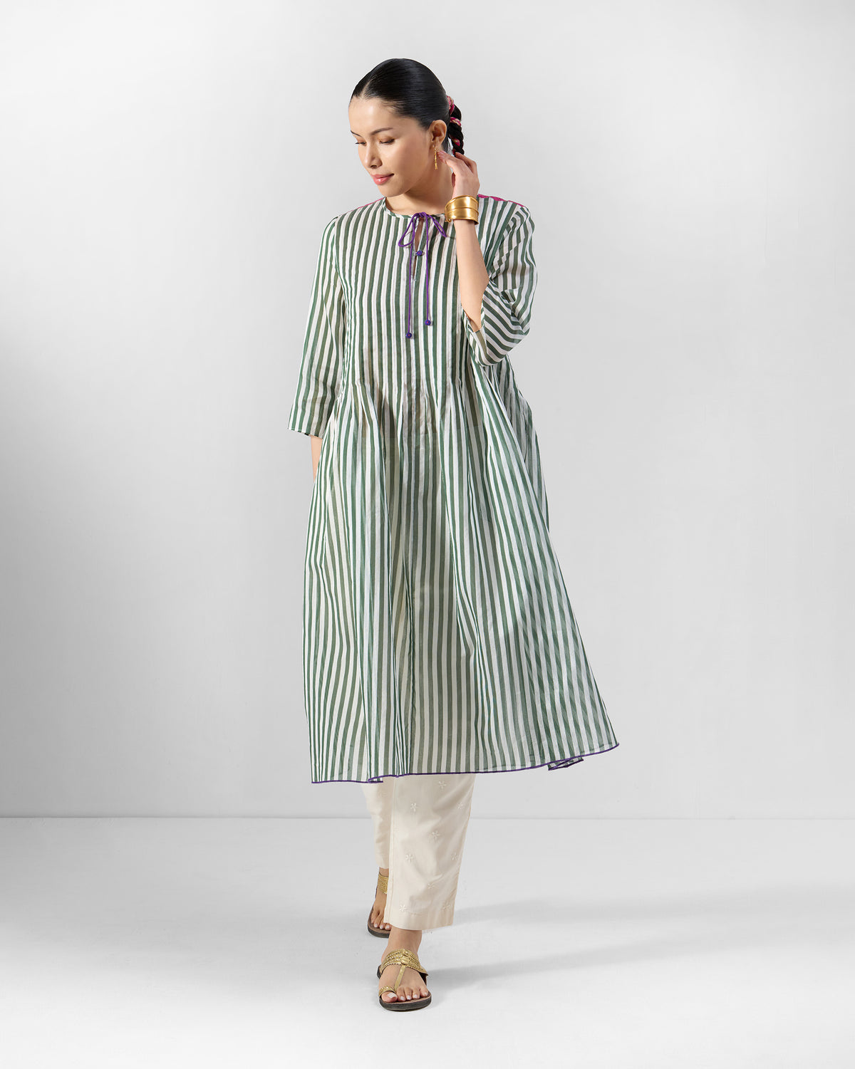 Person wearing a green striped kurta with ivory trousers.