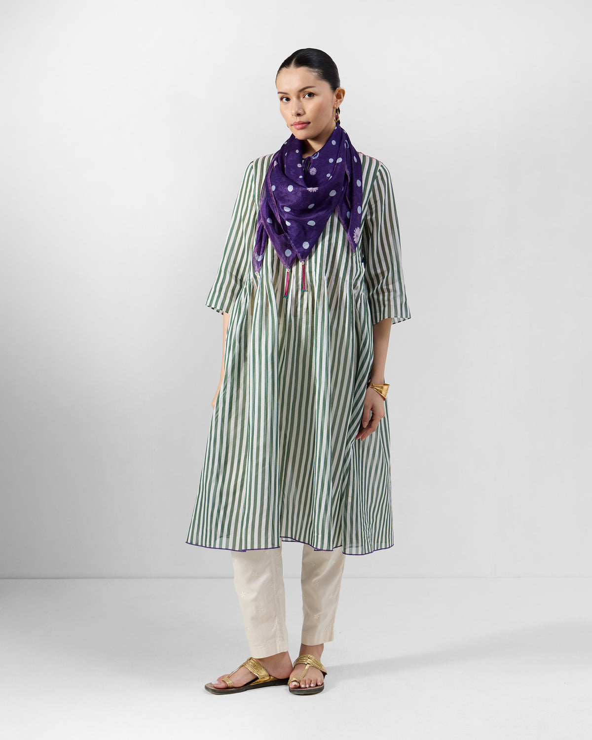 Person wearing a green striped kurta with ivory trousers.