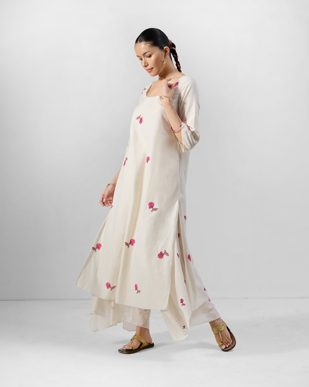 Three-quarter view of an ivory Amrai kurta set with pink floral embroidery.