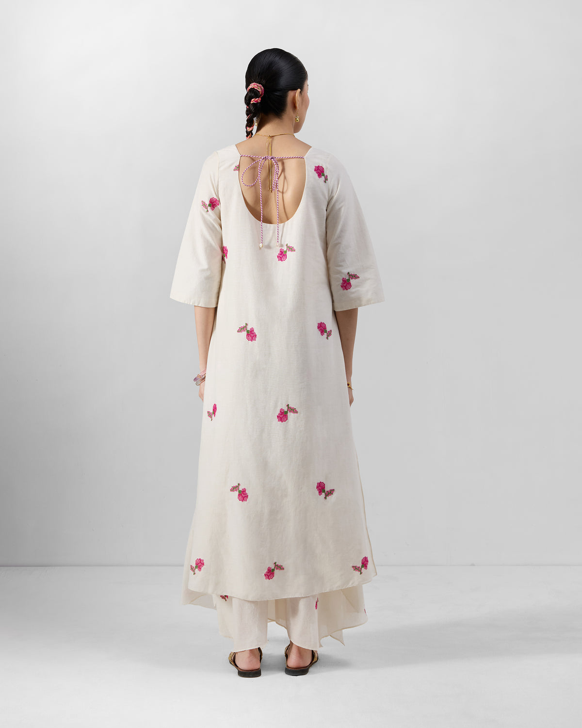 Back of an ivory Amrai kurta with a scoop neckline and pink embroidery.
