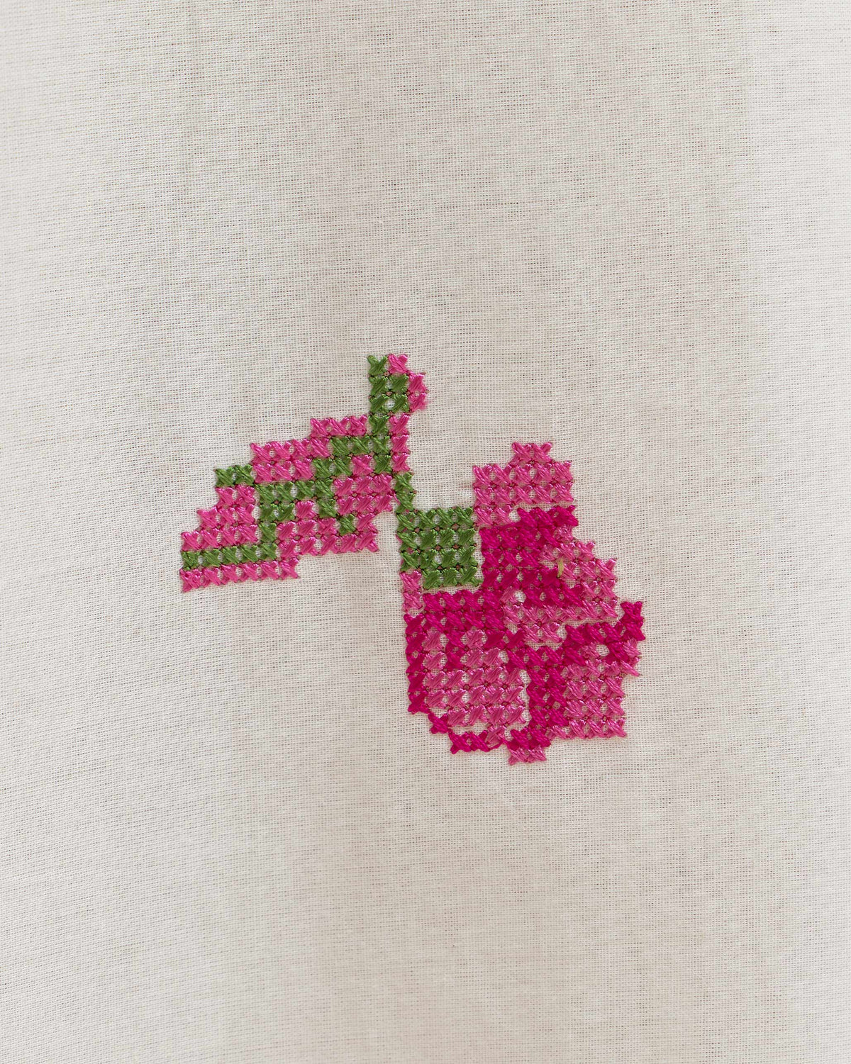 Close-up of pink cross-stitch embroidery on an ivory Amrai kurta set.