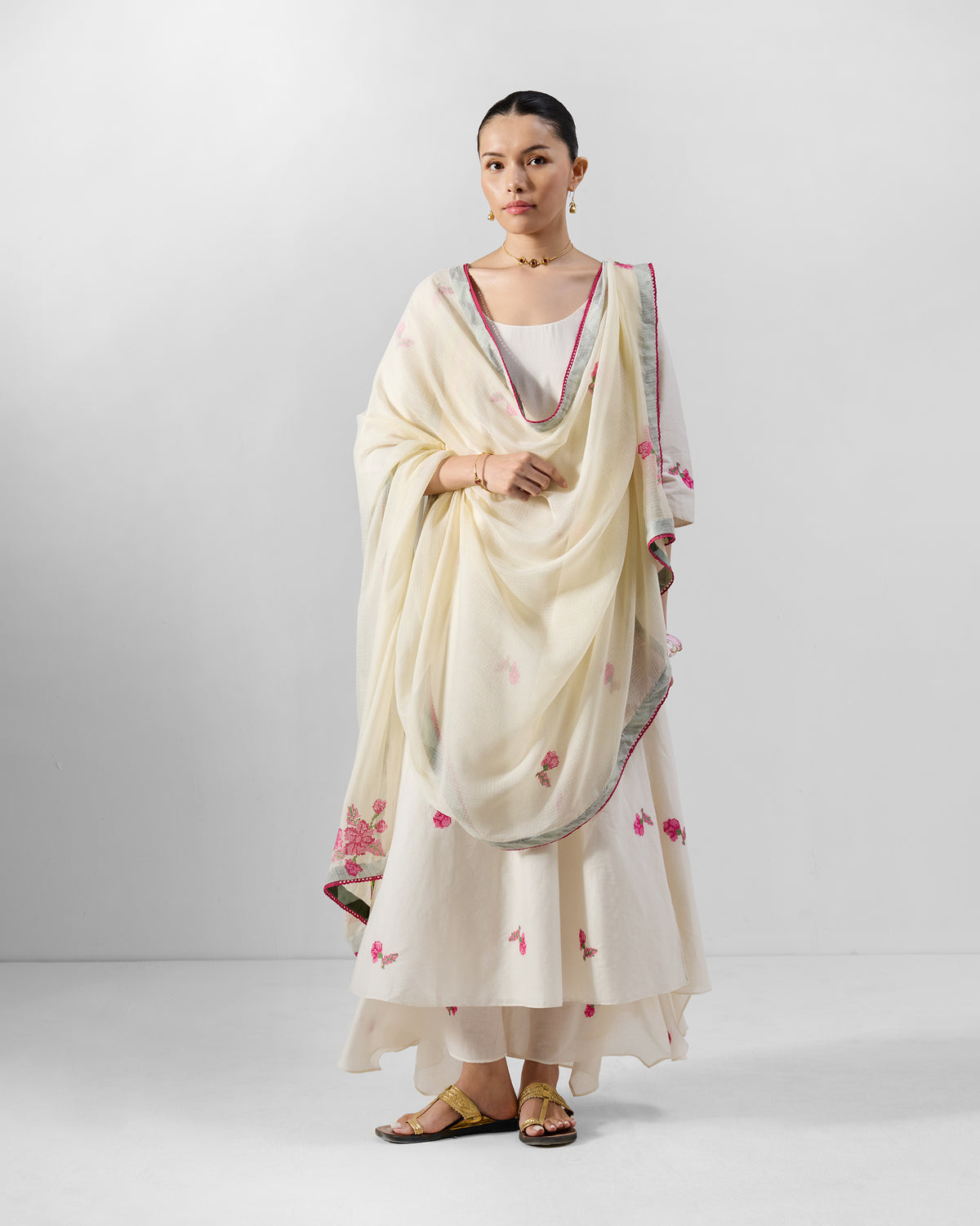 Person wearing an ivory Amrai kurta set with a pink embroidered dupatta.