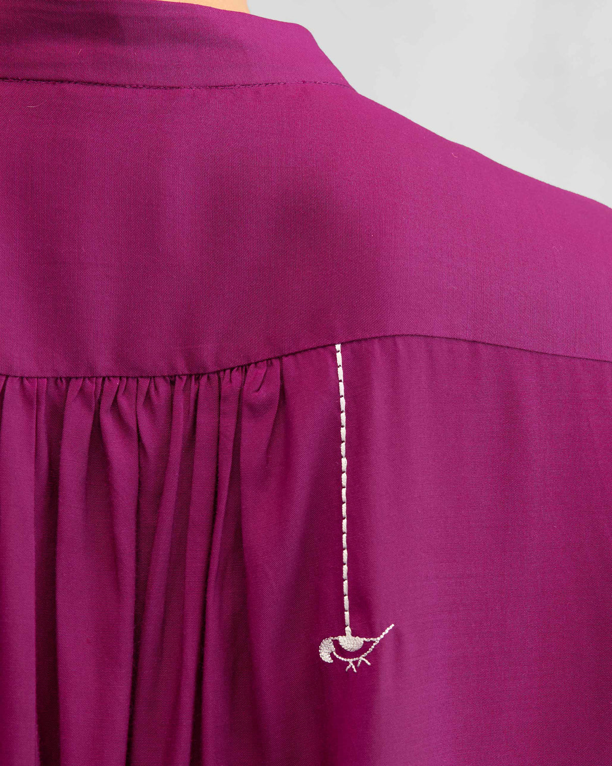 Close-up of a white bird embroidery on a mulberry mandarin top.