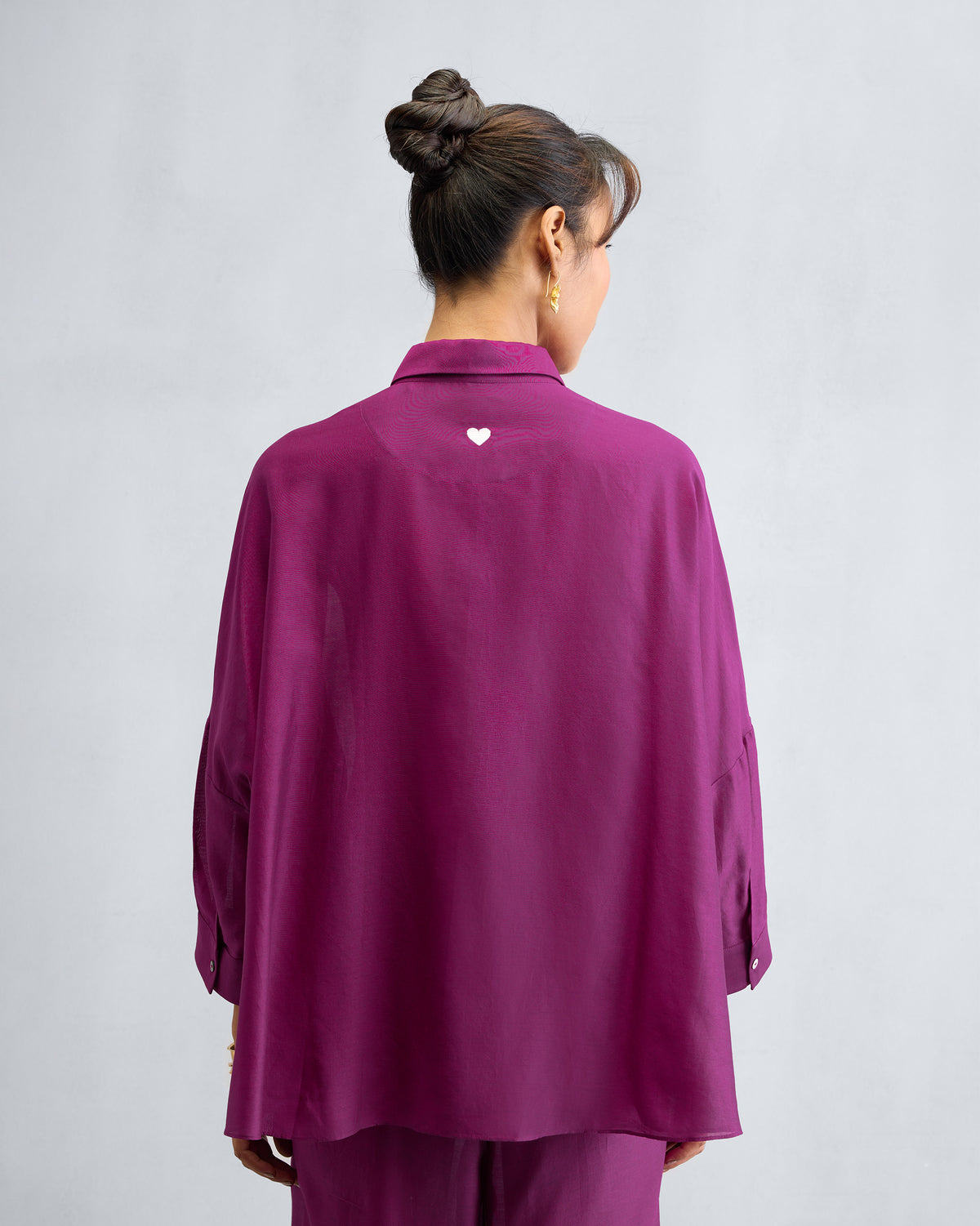 Back of a mulberry boxy shirt with a white heart embroidery.