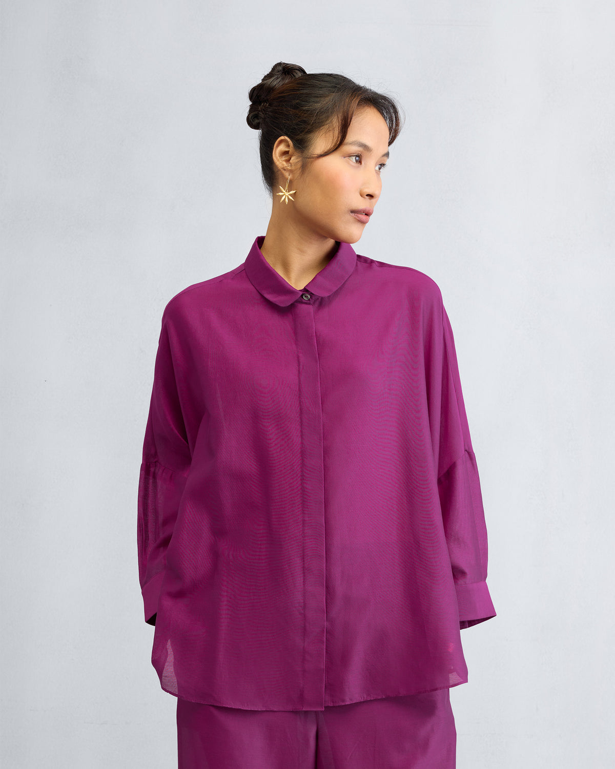 Person wearing a mulberry boxy shirt with a rounded collar and wide cuffs.