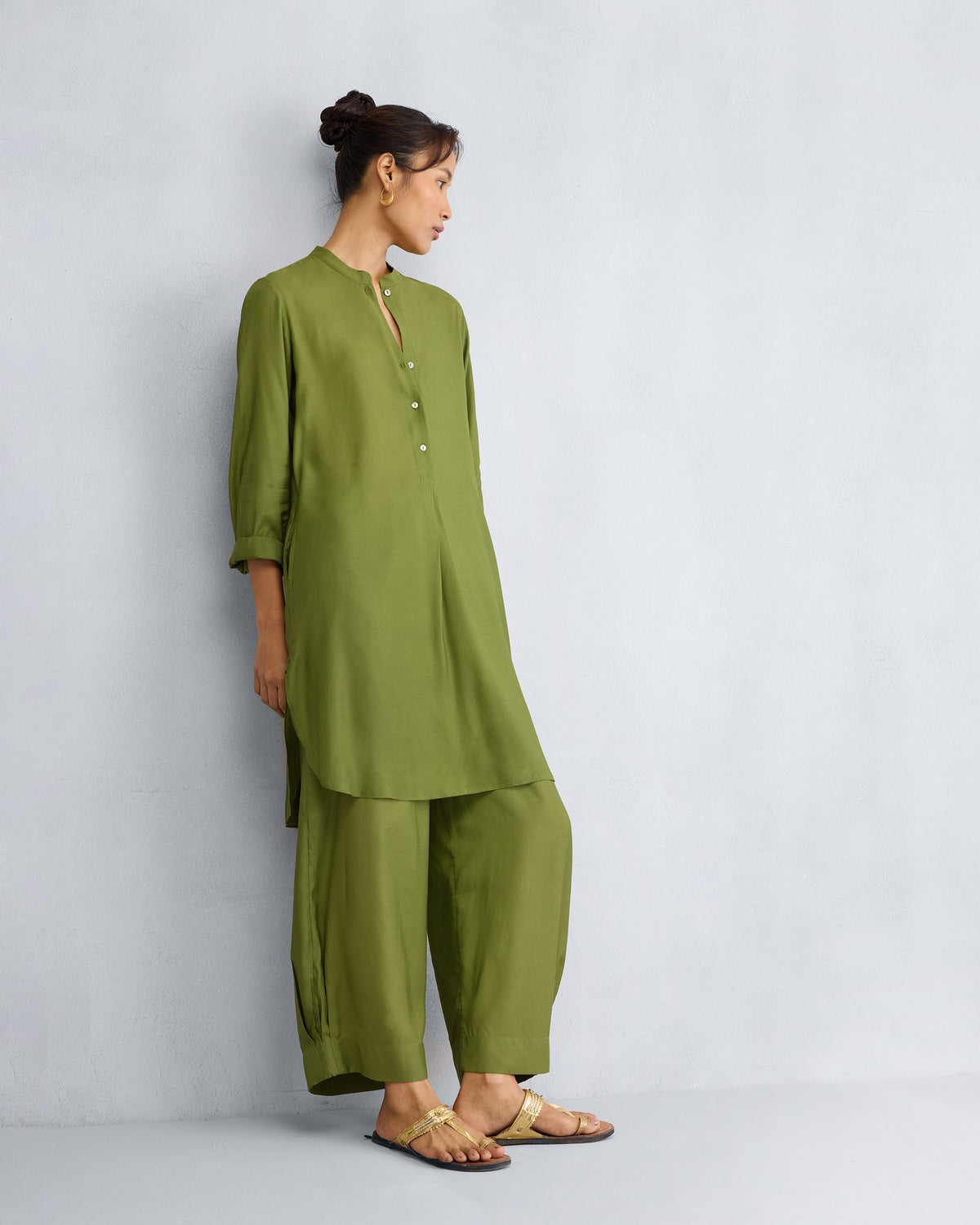 Side profile of an olive mid-length kurta set with a curved hem.