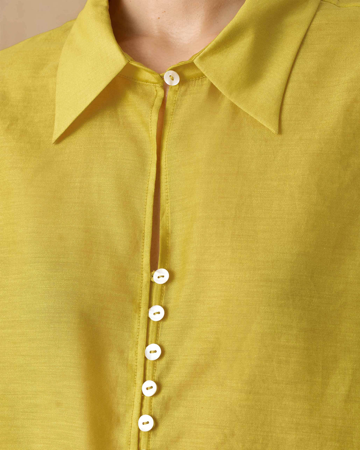 Close-up of a chartreuse tunic collar with a row of small white buttons.