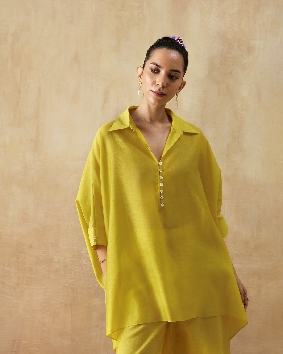 Three-quarter view of a chartreuse oversized tunic with a deep V-neck.