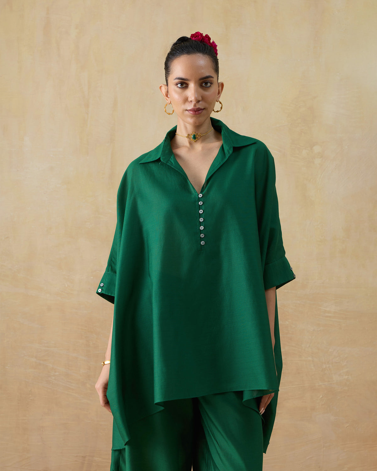Side view of an emerald green Hala tunic with a buttoned V placket.