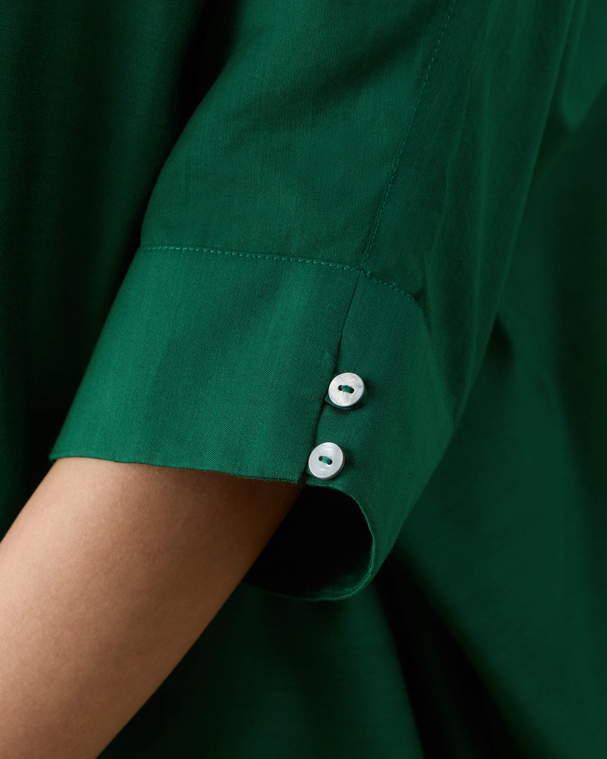 Close-up of a two-button cuff on an emerald green Hala tunic sleeve.