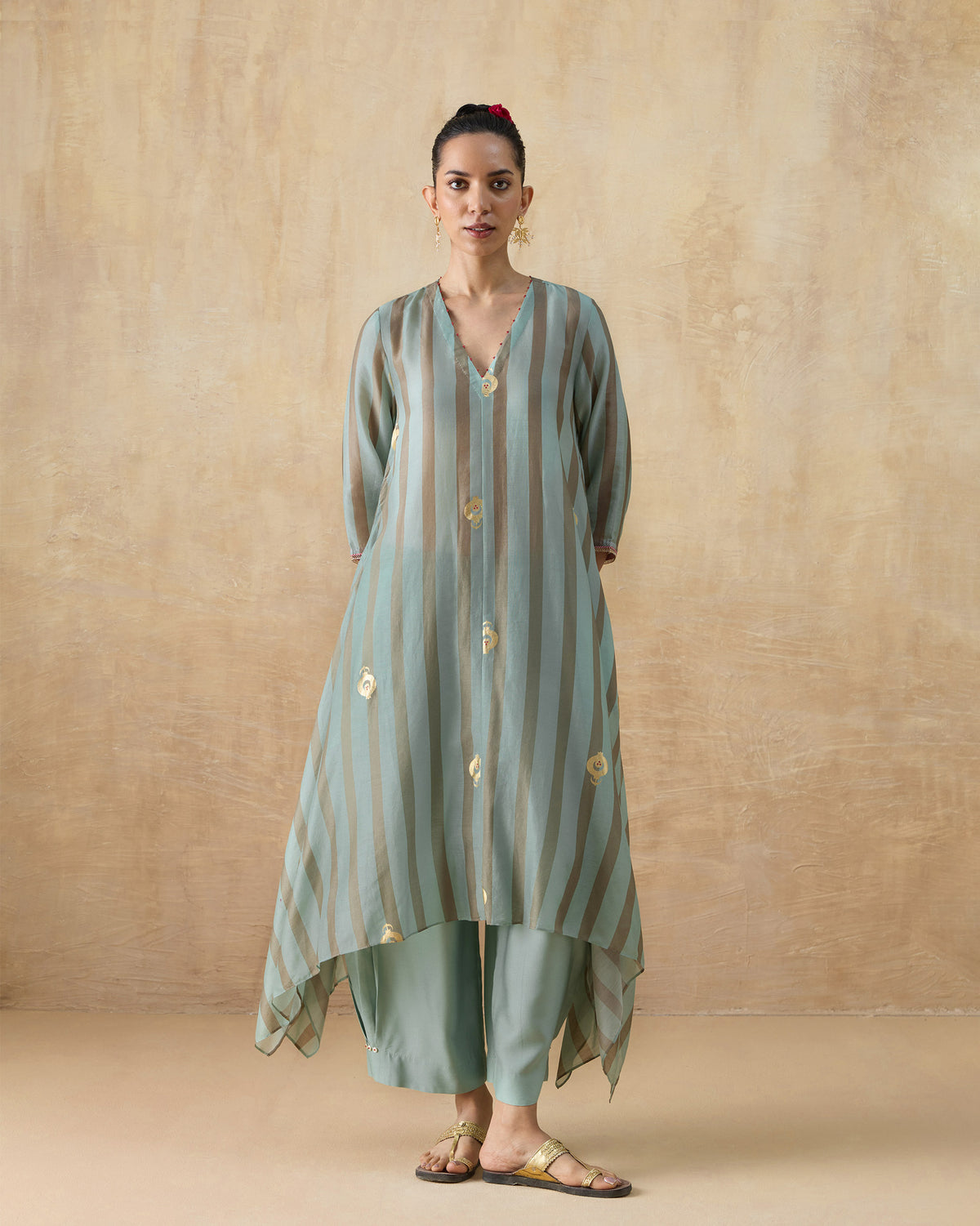 Person wearing a green and tan striped Midnight Club Kurta Set with gold foil motifs.