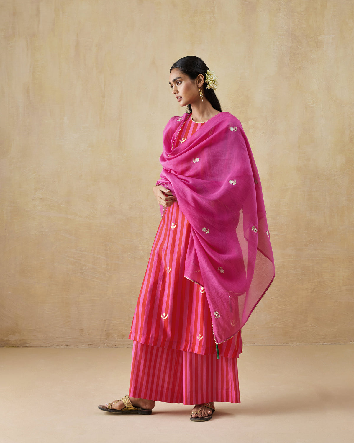 Person wearing a red and berry striped kurta set with a sheer pink dupatta.