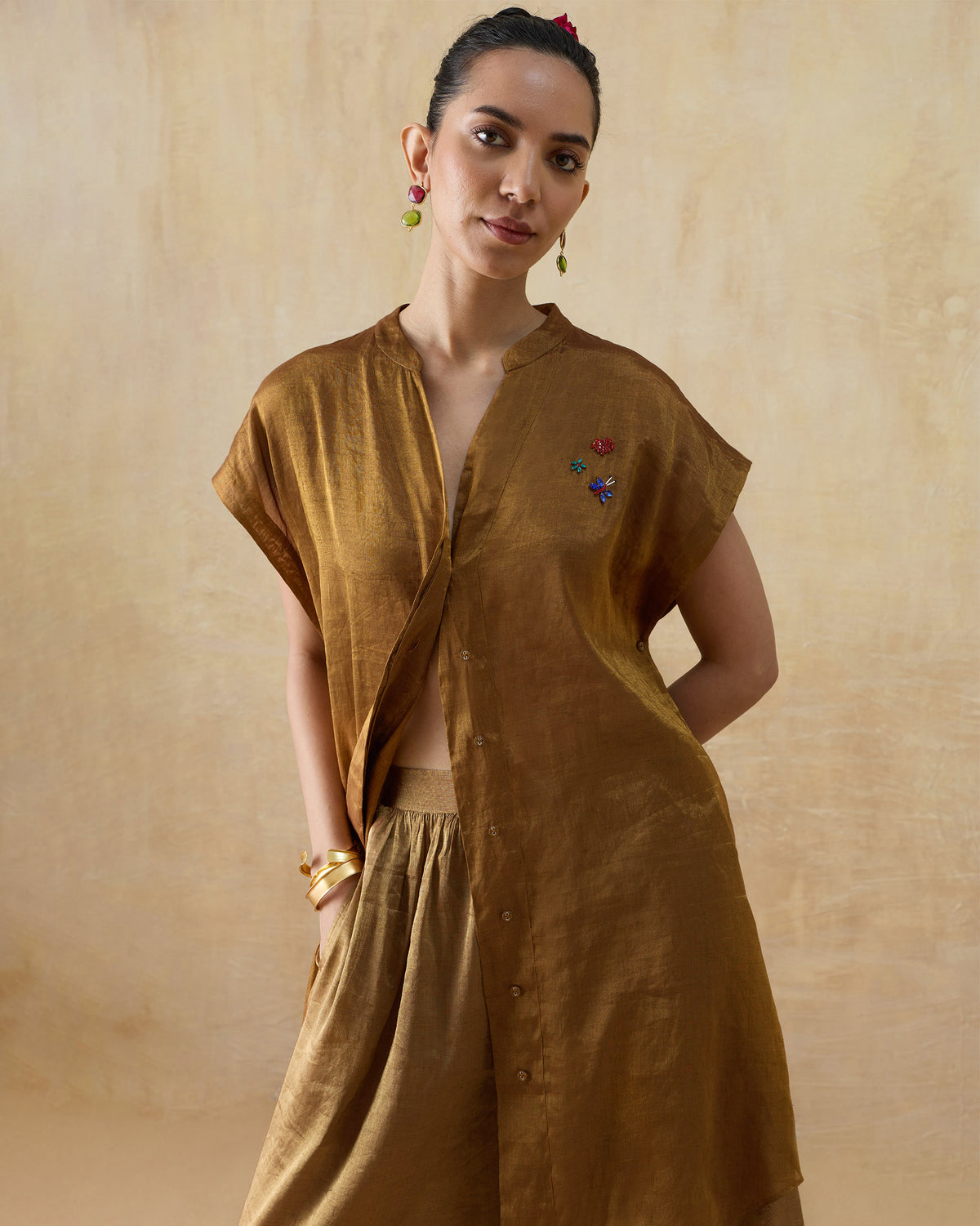 Metallic gold shirt with colourful chest embroidery and wide-leg pants.