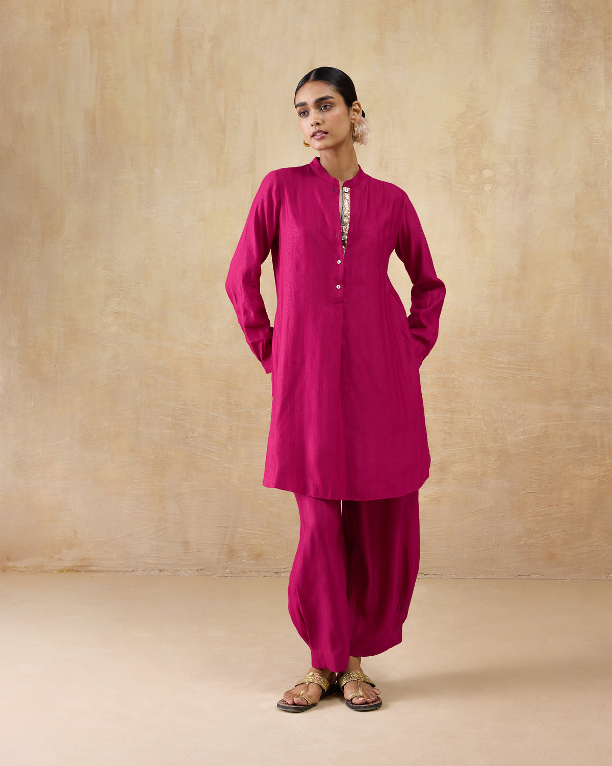 Person wearing a berry pink long kurta set with long sleeves and matching pants.
