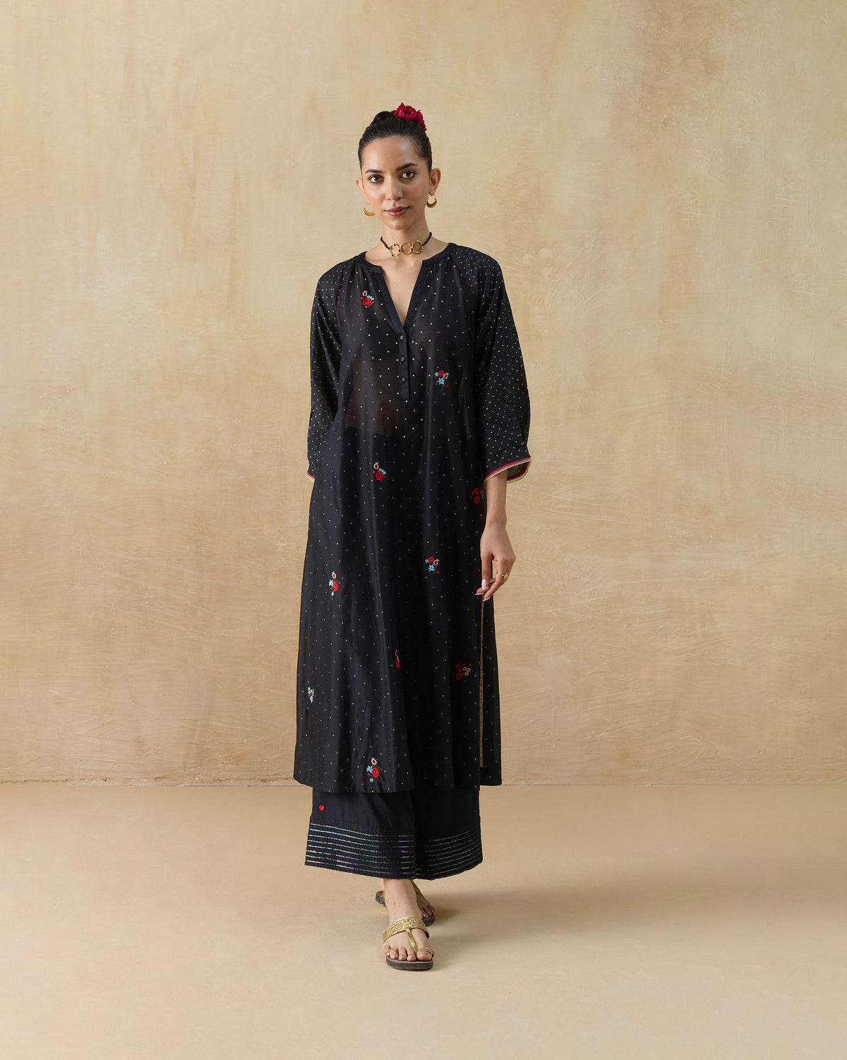 Person wearing a black Moonbeam kurta set with scattered florals and striped pant hems.