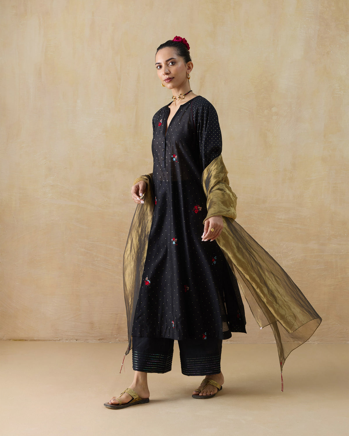Person wearing a black Moonbeam kurta set with a shimmering gold dupatta.