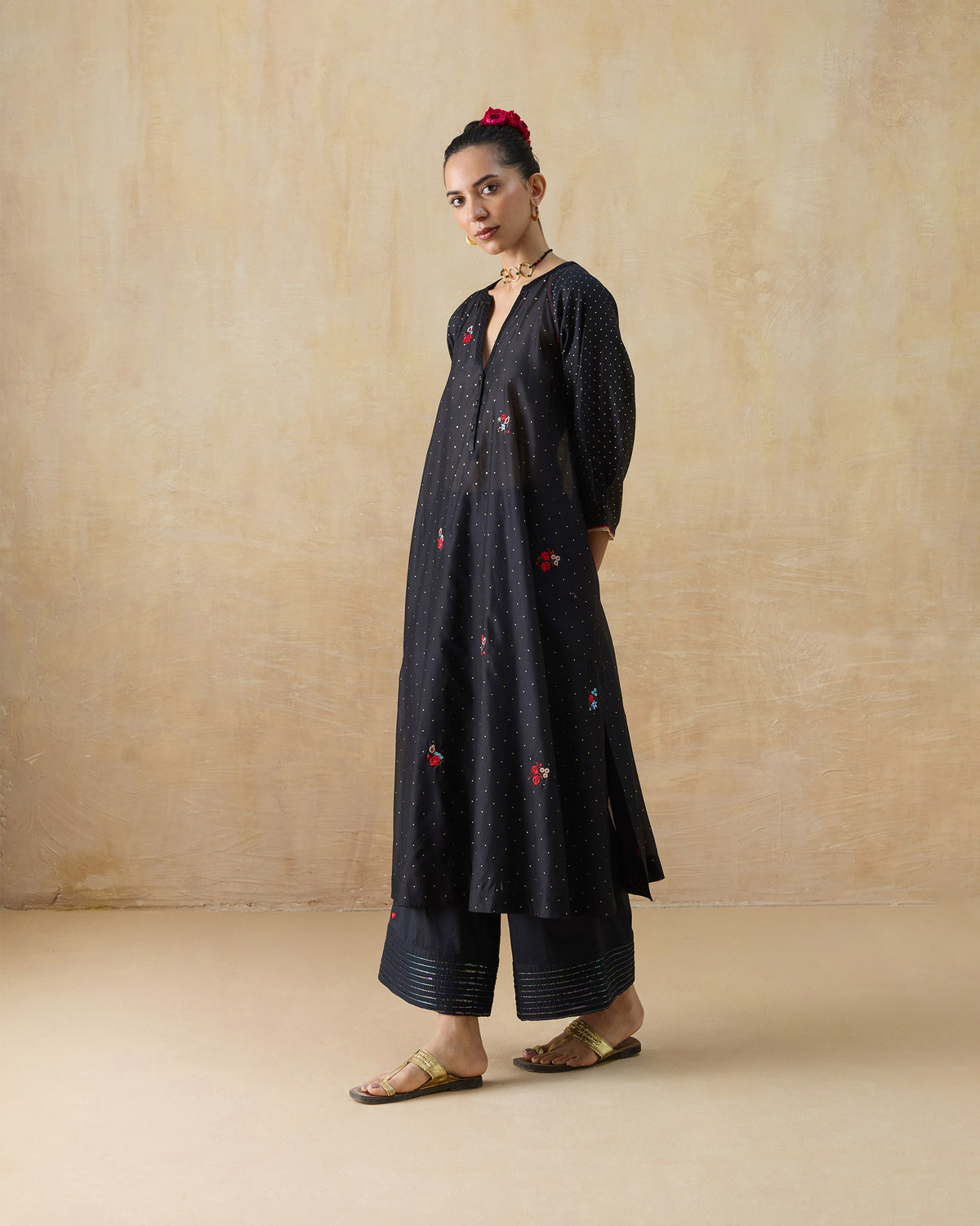 Side view of a black Moonbeam kurta set showing the side slit and striped pant hems.