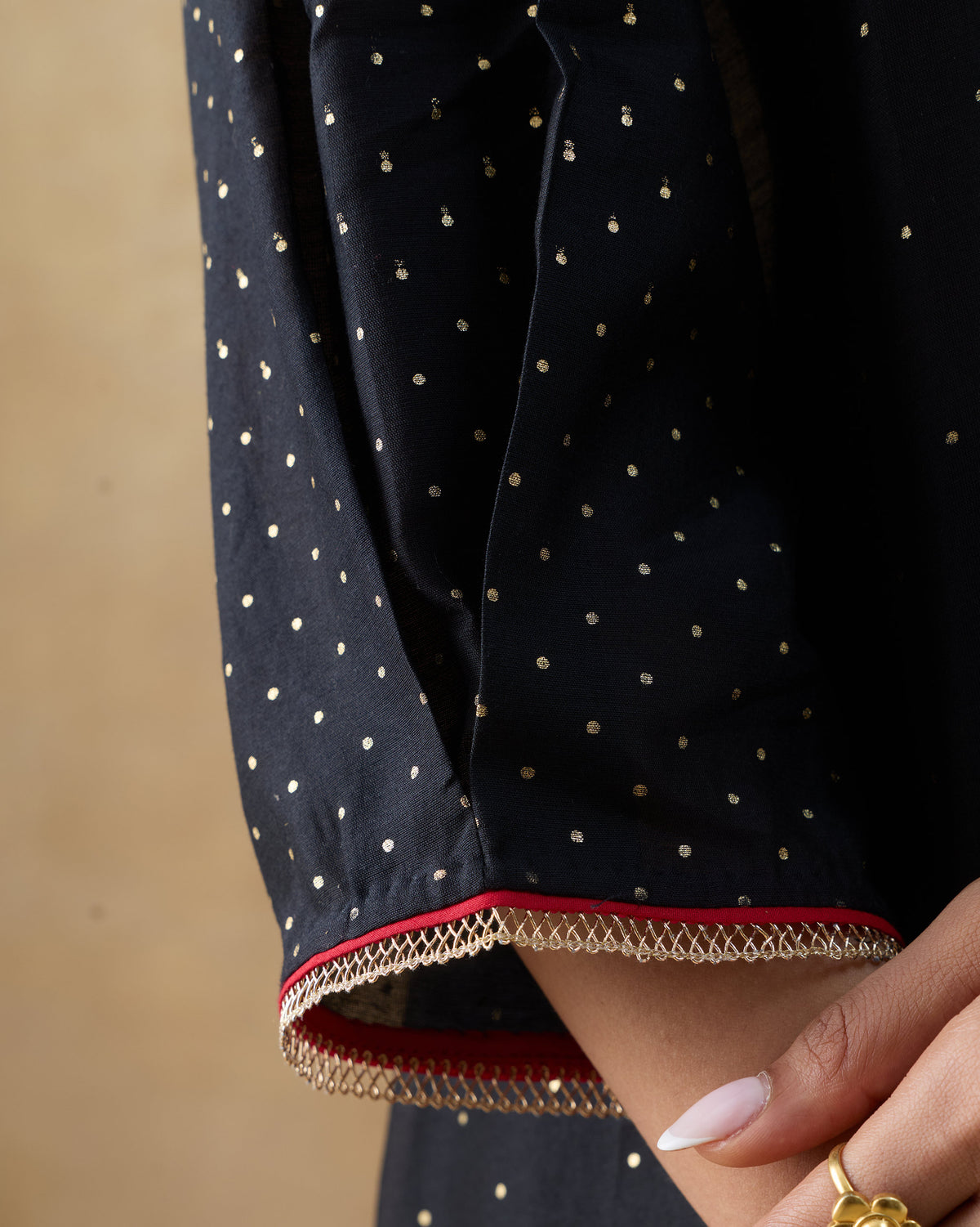 Close-up of a Moonbeam kurta sleeve cuff with red piping and gold trim.