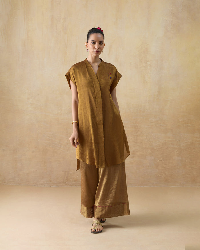 Person wearing the Tango Kaftan Set in bronze gold with a band collar and wide trousers.