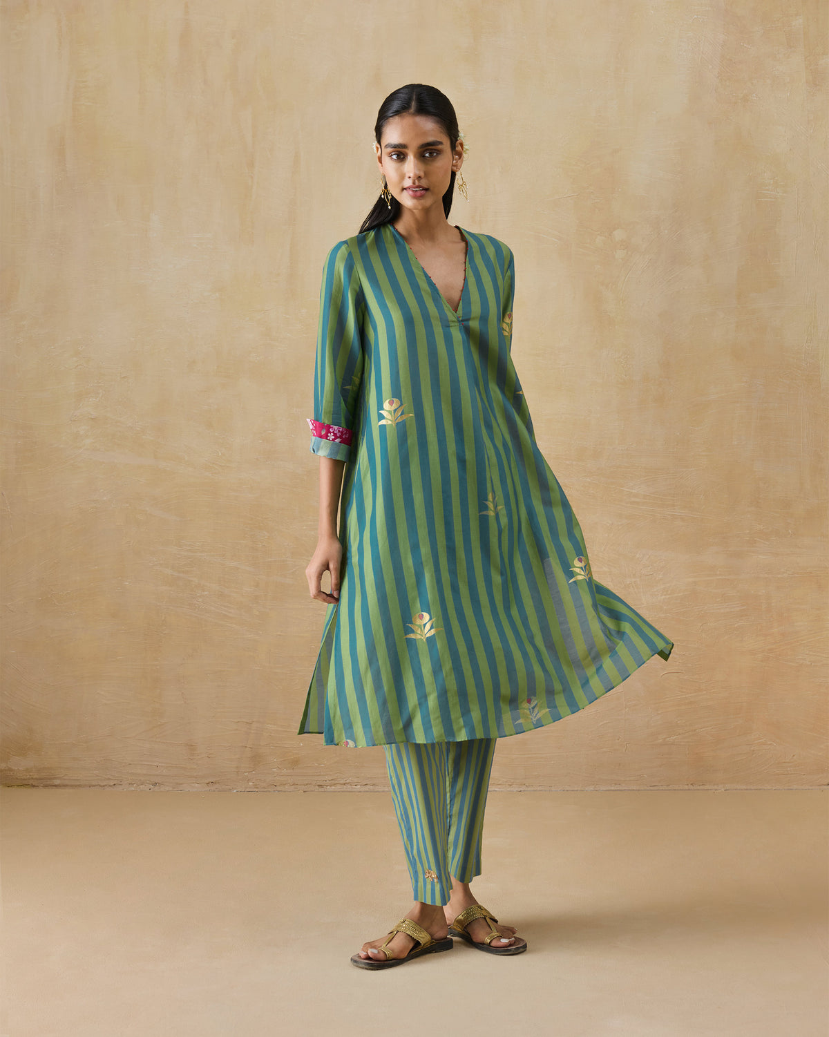 Person wearing a green striped Front Pleated Kurta Set with magenta cuff lining.