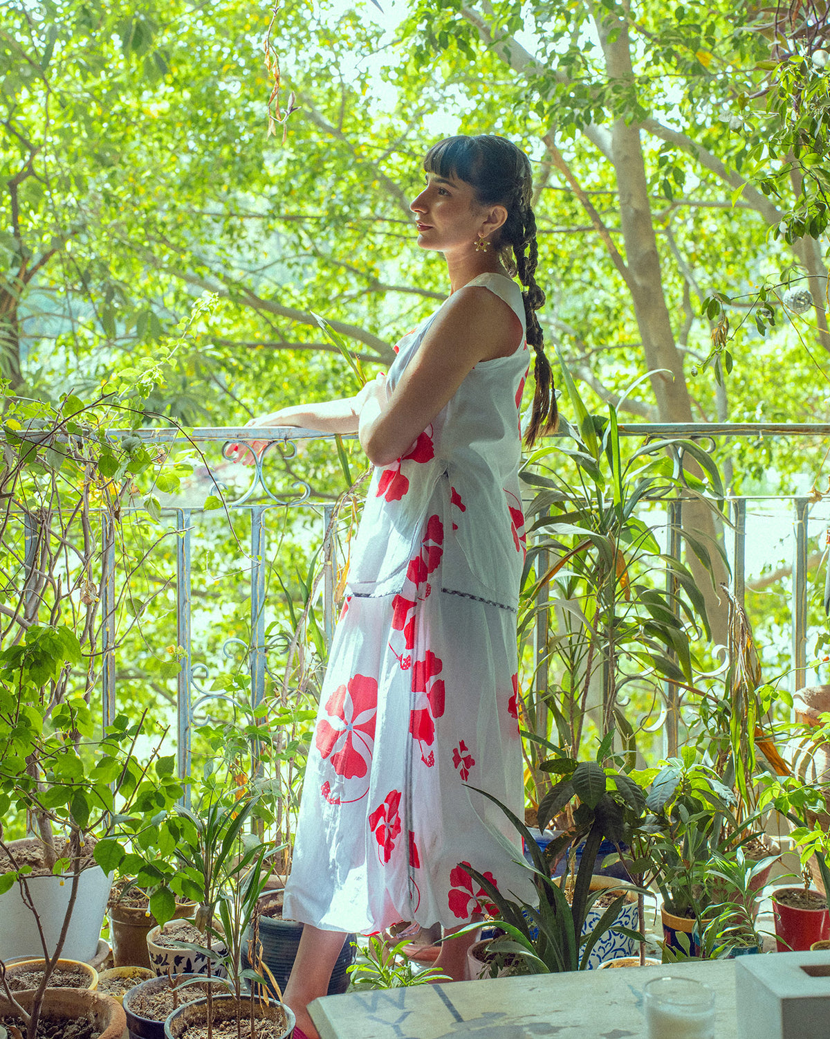 Person in a matching white and red hibiscus Kiva top and skirt on a balcony.