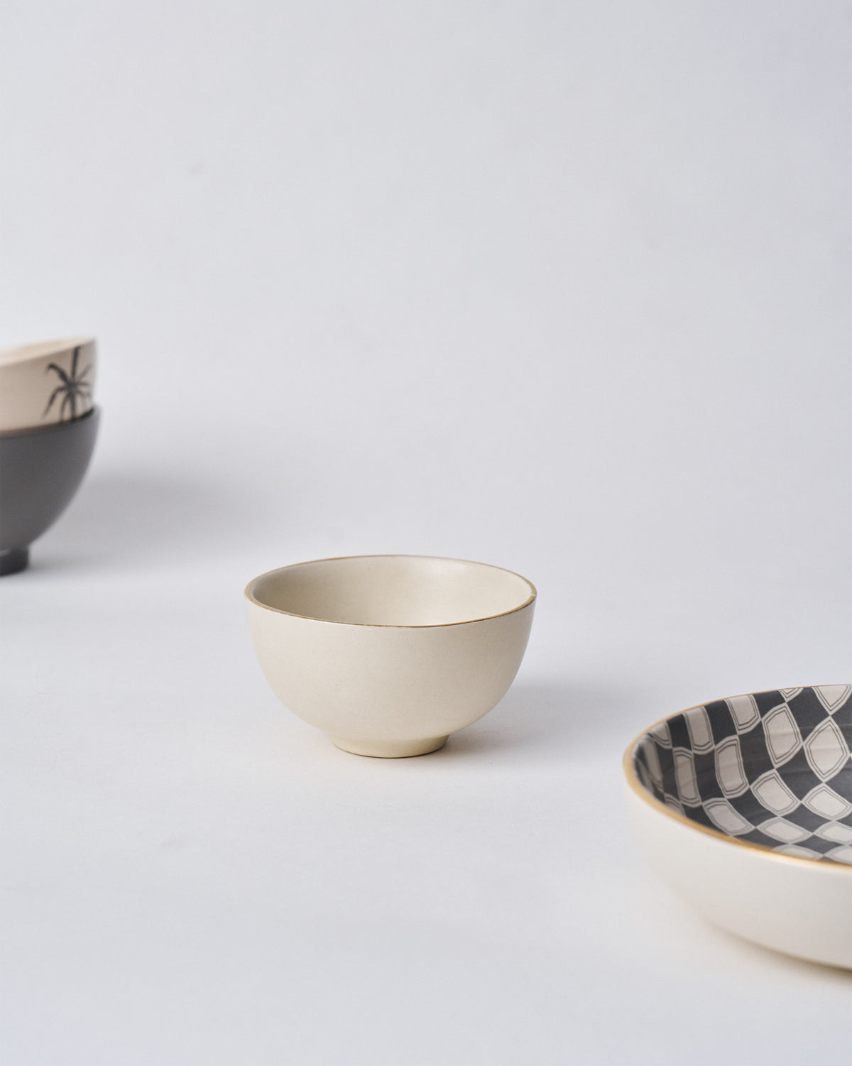 Tara Katori cream bowl beside black-patterned bowls.