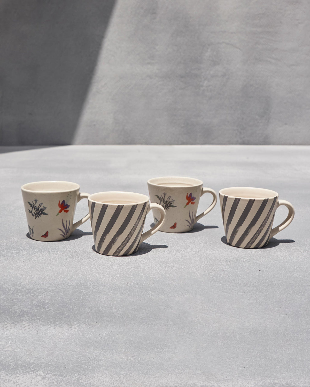 Set of four ivory Nanjing espresso mugs in stripe and blossom prints.