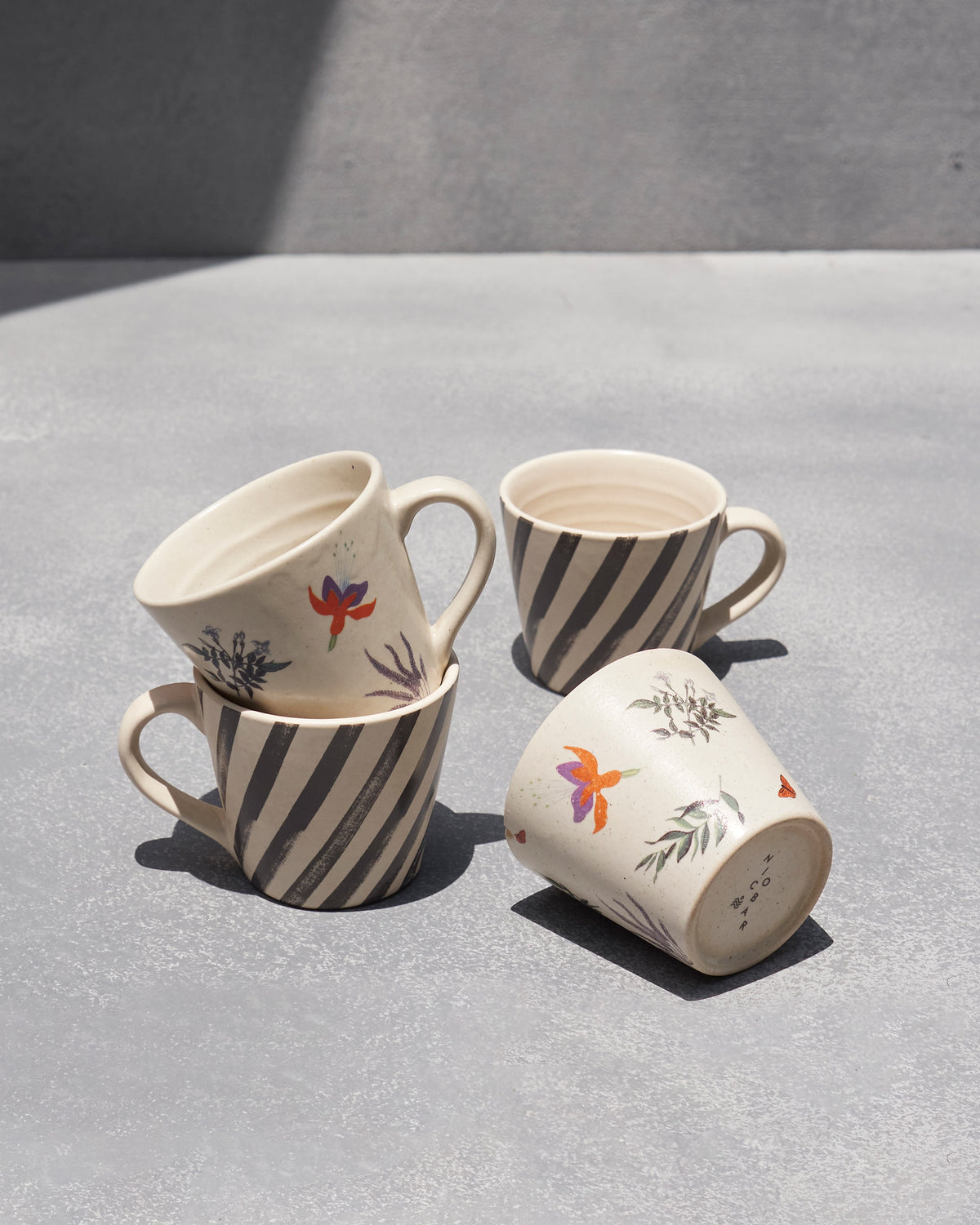 Nanjing espresso mugs in charcoal stripe and floral prints, nested and tipped.