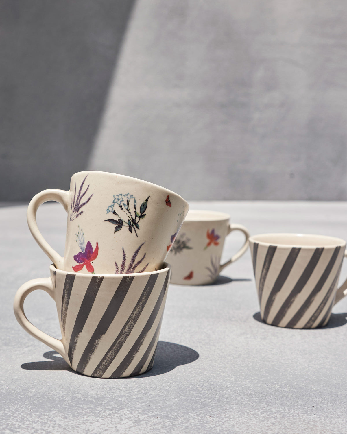 Ivory Nanjing espresso mugs showing fuchsia blossoms and charcoal diagonal stripes.