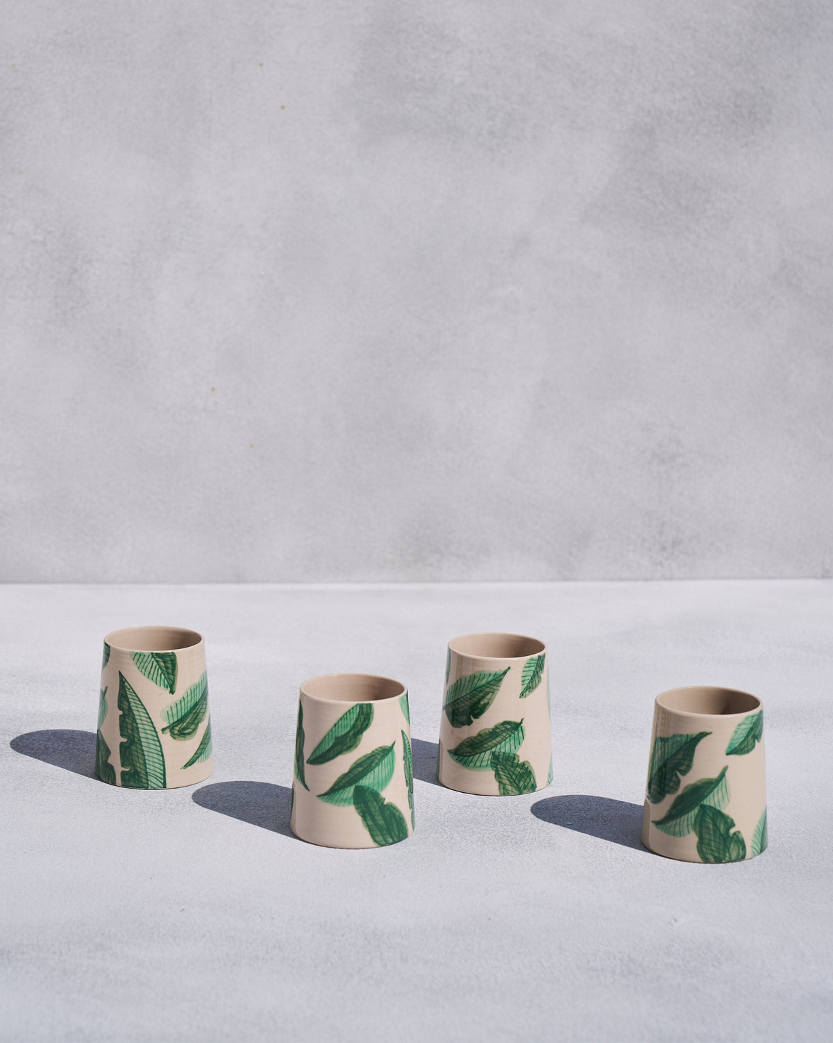 Four staggered Galle kulhars with green banana leaf print.
