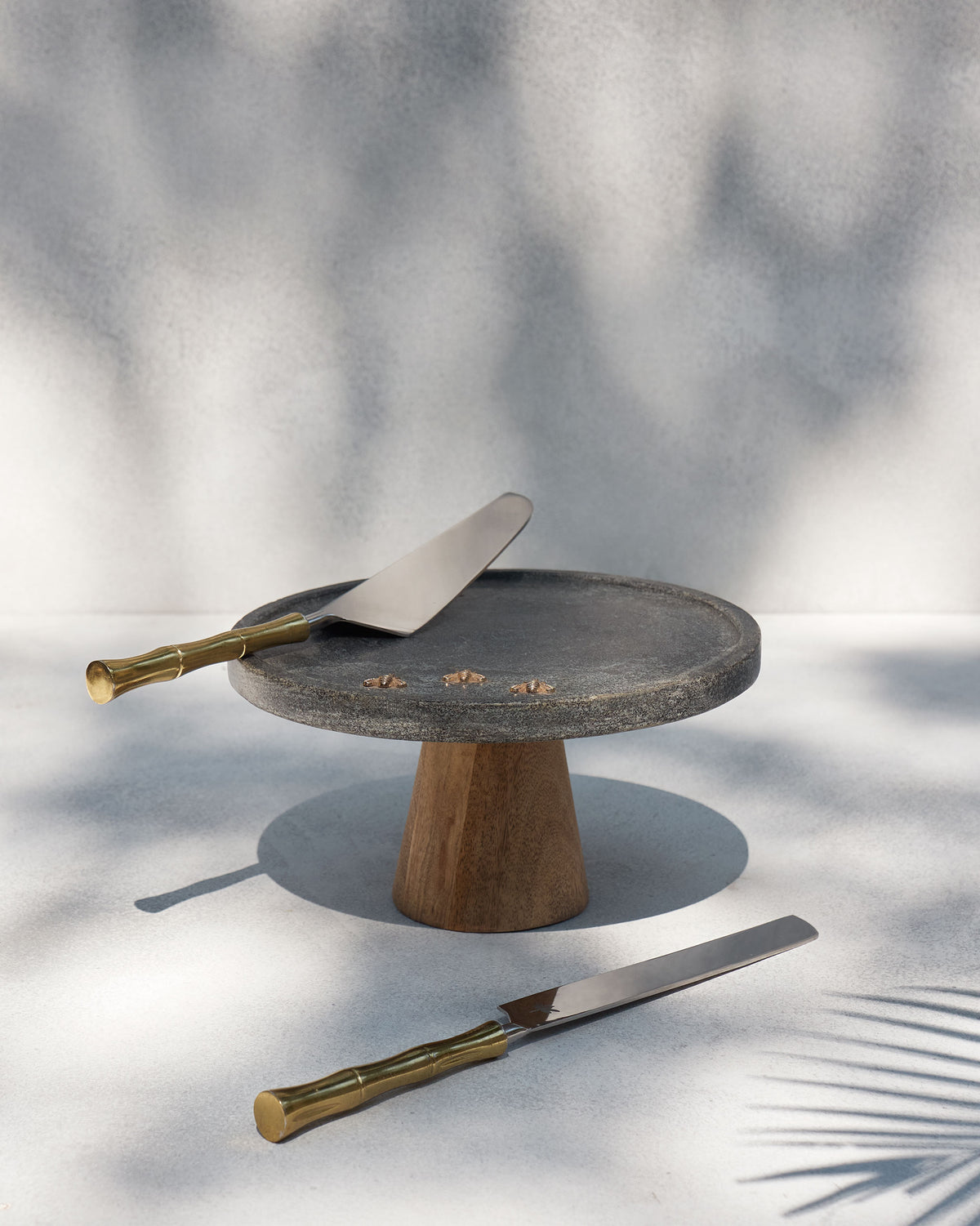 Firefly cake stand with gold fireflies styled beside a cake knife and server.
